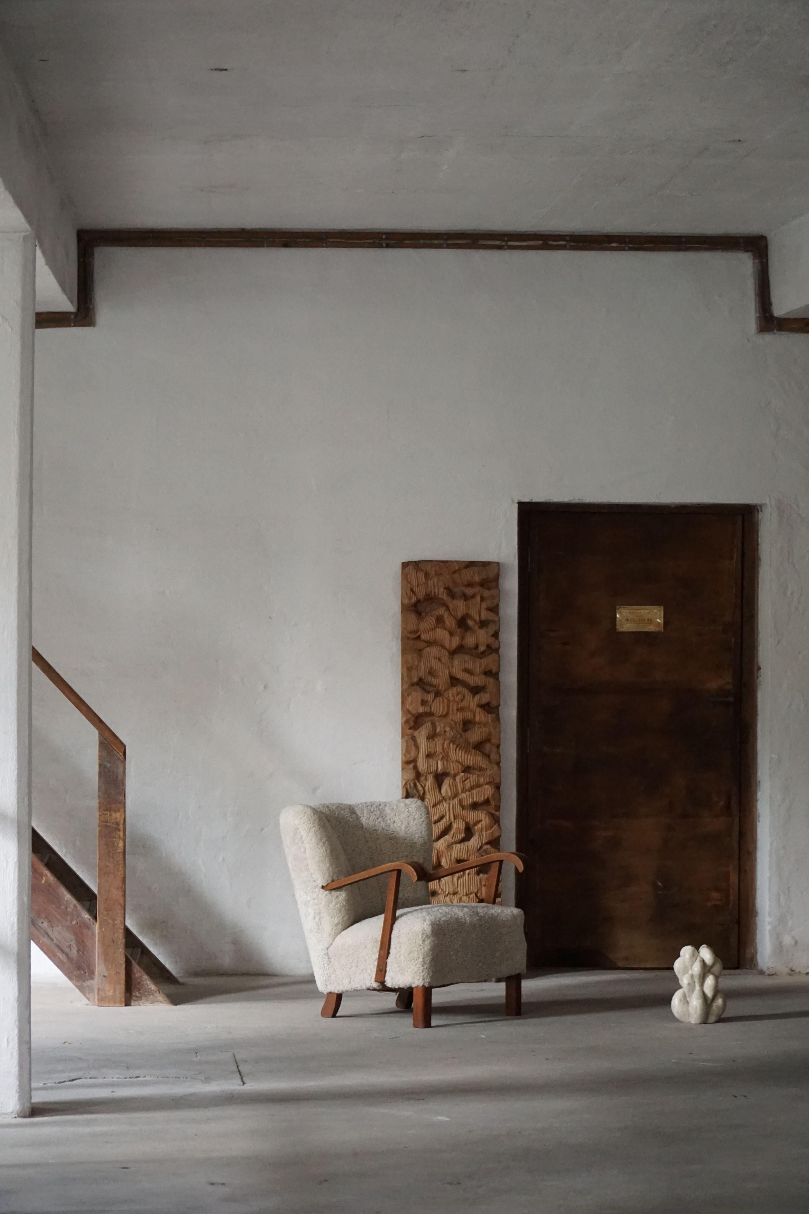 Una sedia lounge danese moderna e senza tempo, con braccioli in rovere massiccio e una scocca rivestita di recente in lana d'agnello shearling di alta qualità. Realizzato da un abile ebanista danese negli anni '50, questo pezzo cattura l'essenza del