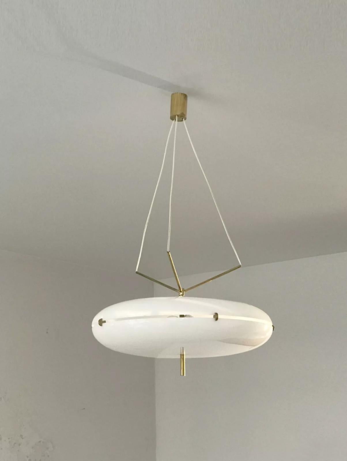 A spectacular aerial suspension or chandelier, Modernist, Space-Age, Forme-Libre, UFO-inspired ovoid body in white diffusing Perspex, structure and finishes in bronze or gilded brass, unique 3-wire suspension system connected within a triangular