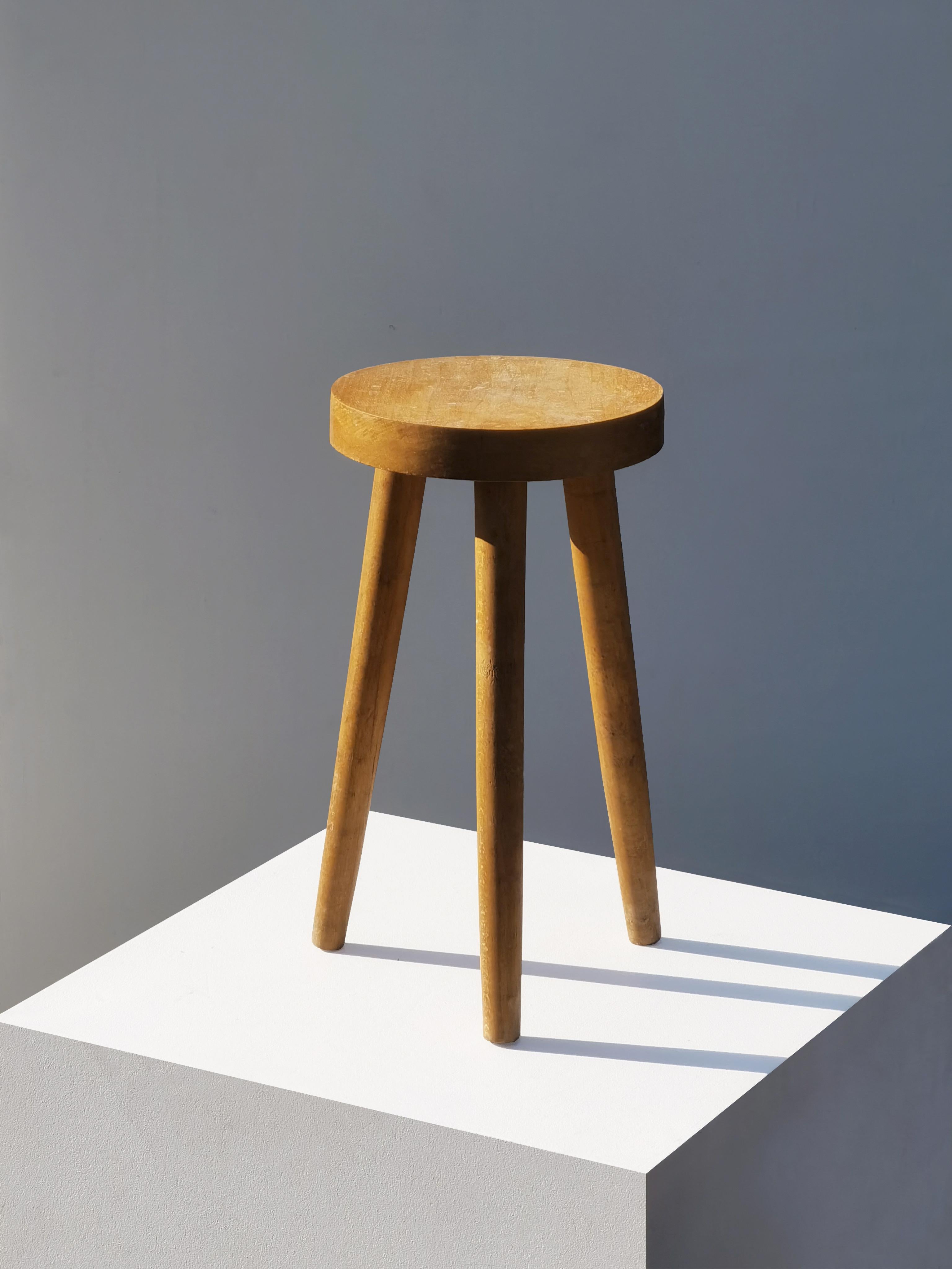 un seul tabouret tripode, Mid-Century Modern, Modernist, Rustic Modern, Brutalist, structure tripode solide et architecturale en orme massif, 3 pieds hauts aux formes douces, un plateau d'assise circulaire petit mais massif, dans l'esprit des