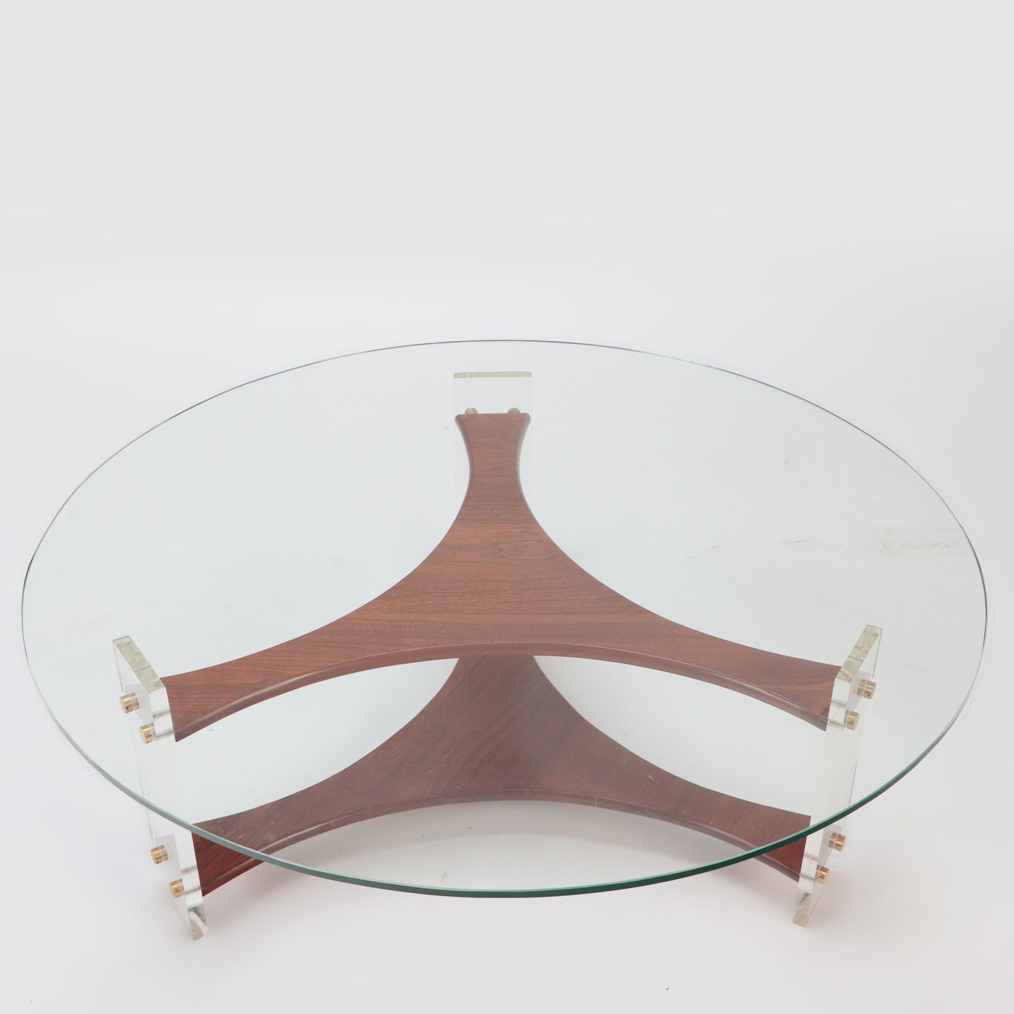 A mid-century round coffee table with Italian walnut base and lucite legs and brass details. Circa 1960.