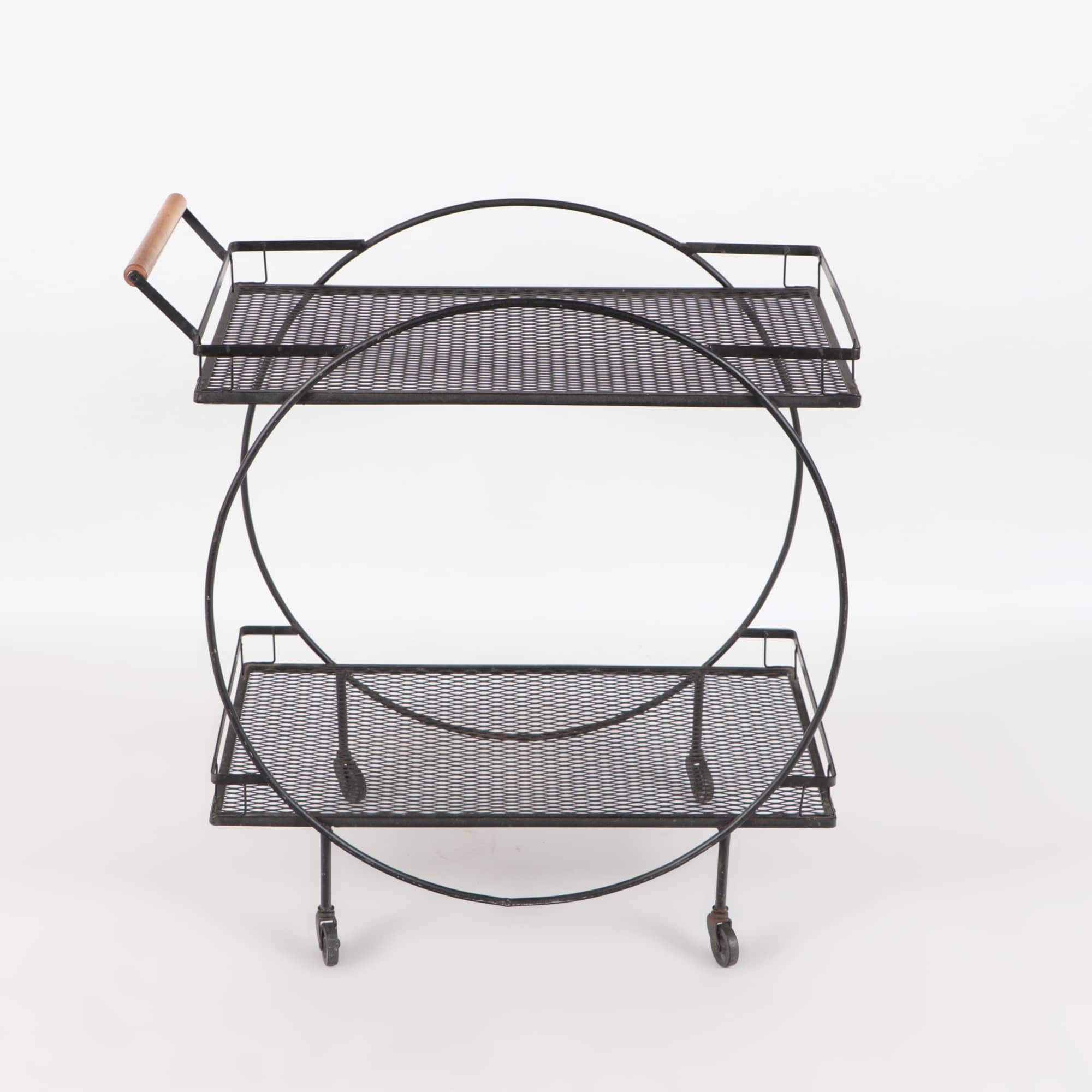 A Mid-Century Modern Salterini Maurizio Tempestini wrought iron bar or serving cart having a circular black frame with two metal mesh shelves all supported by four rubber casters. The round handle bar is fashioned from maple circa 1950.