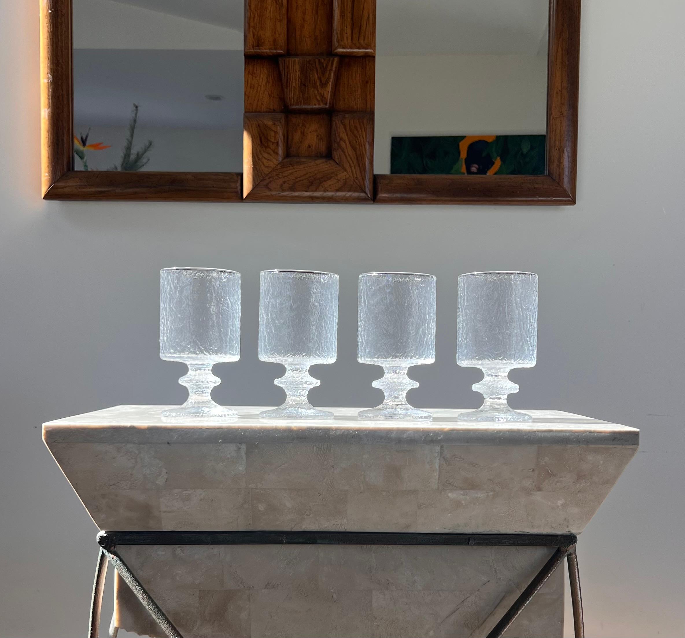 A mid century modern set of four glass water goblets designed by Timo Sarpaneva for LASIA, Finland 1960s. These glasses have a special corrugated pattern akin to almost tree bark, but in hand-crafted thick glass. They come in their original