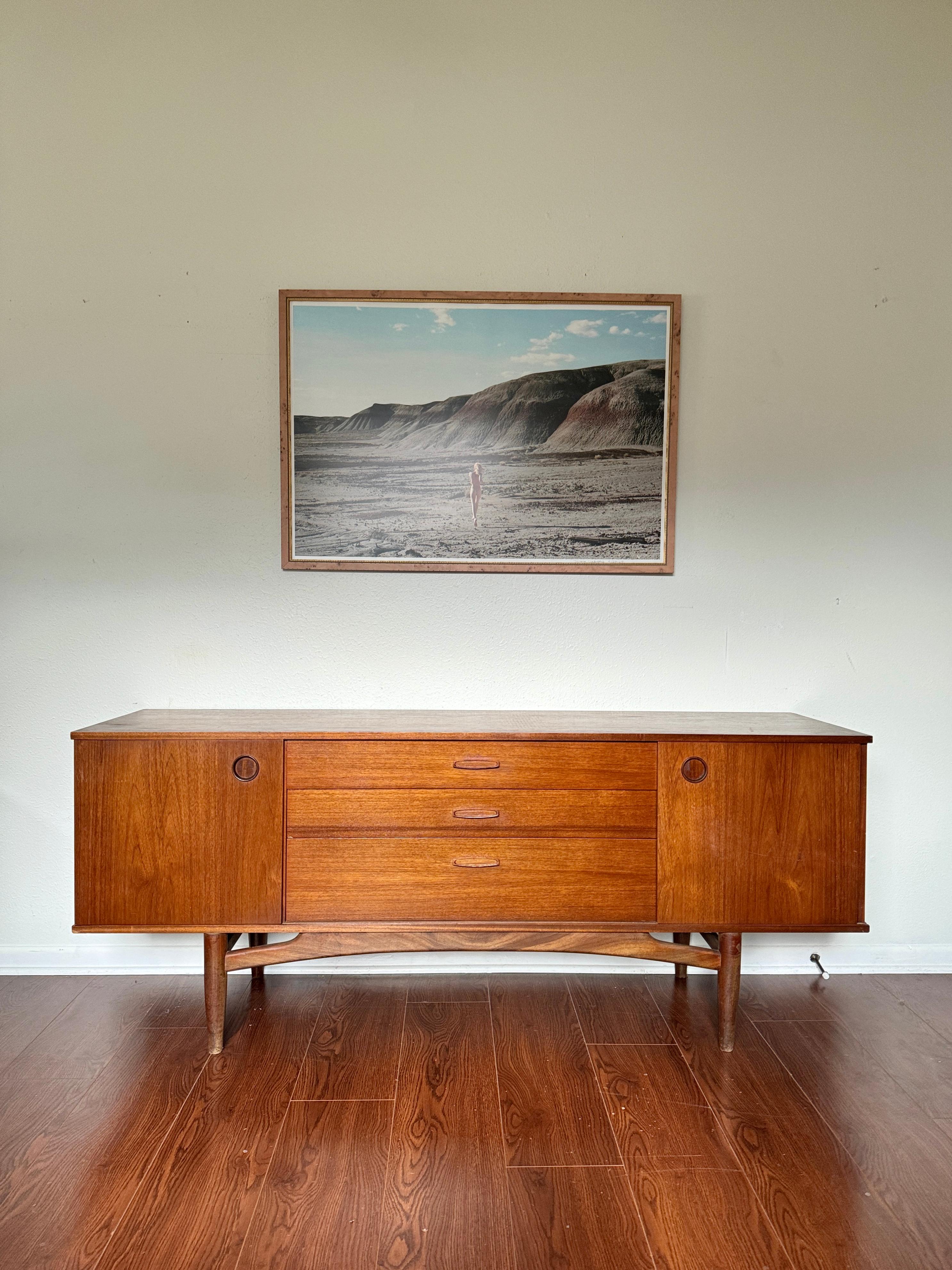 A mid century modern sideboard by Avalon, circa 1960s. With plenty of storage space, the two sliding doors reveal removable shelved storage and a central bank of three dovetailed drawers. Overall in good original condition. Structurally sound and