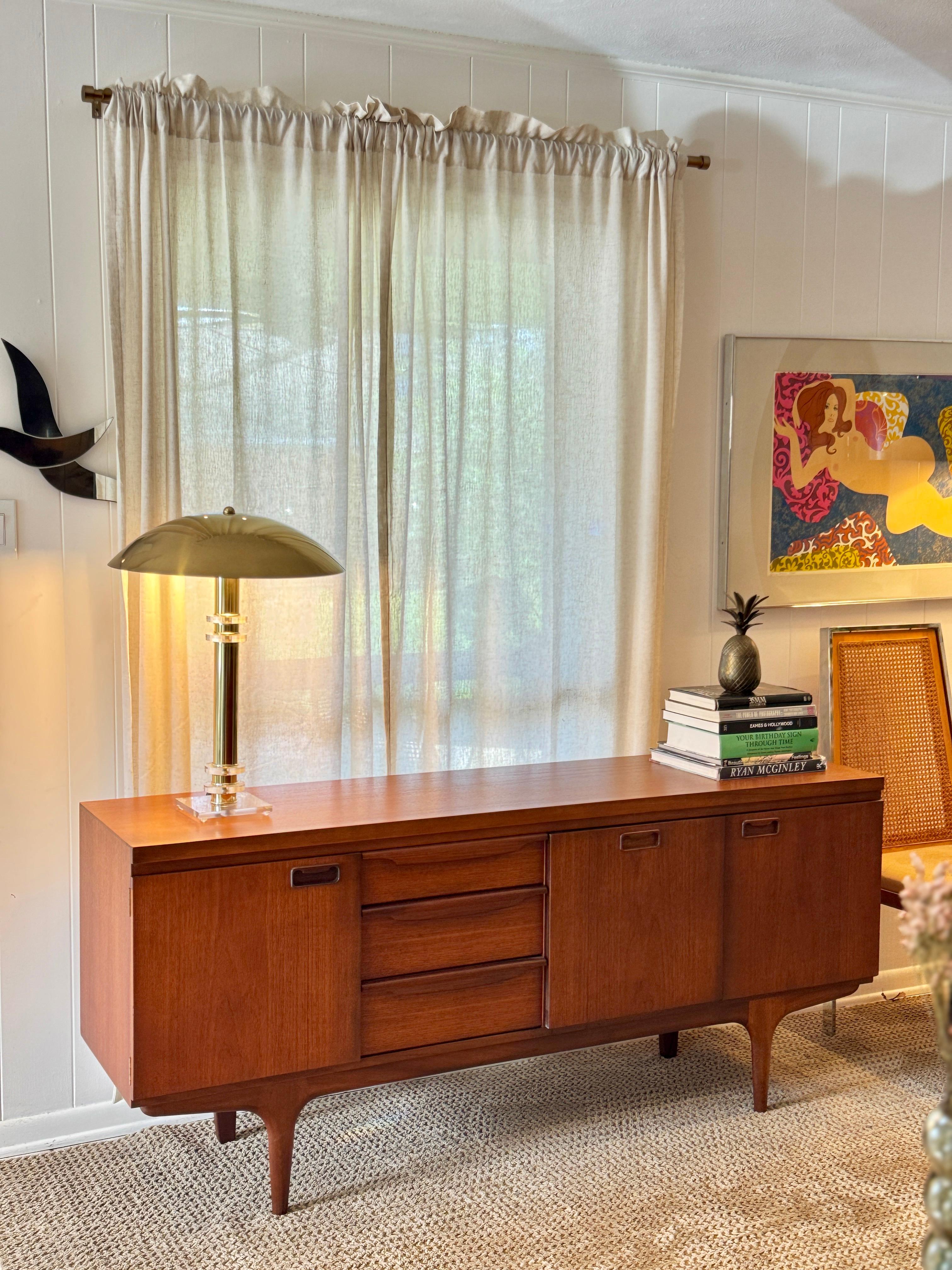A mid century modern sideboard by renowned British furniture maker Greaves & Thomas, circa 1960s. Made from richly grained teak, it features sculpted recessed handles, seamless joinery, and tapered legs, highlighting the commitment to both