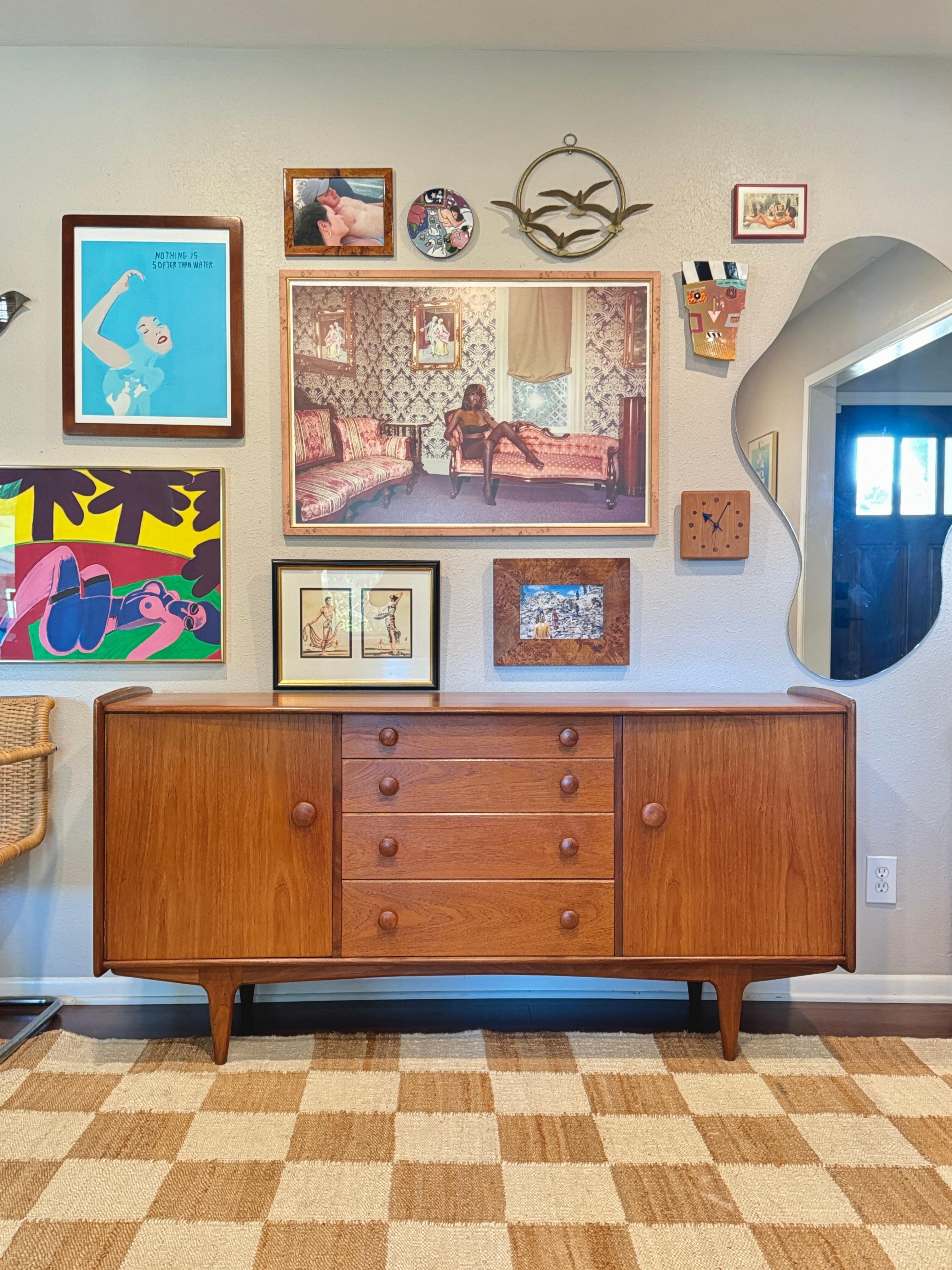 A mid century modern solid teak credenza designed by John Hebert for British manufacturer Younger Furniture, circa 1960s. It features four drawers of staggered depth. The top drawer features a cutlery divider. Each of the two cabinets has a