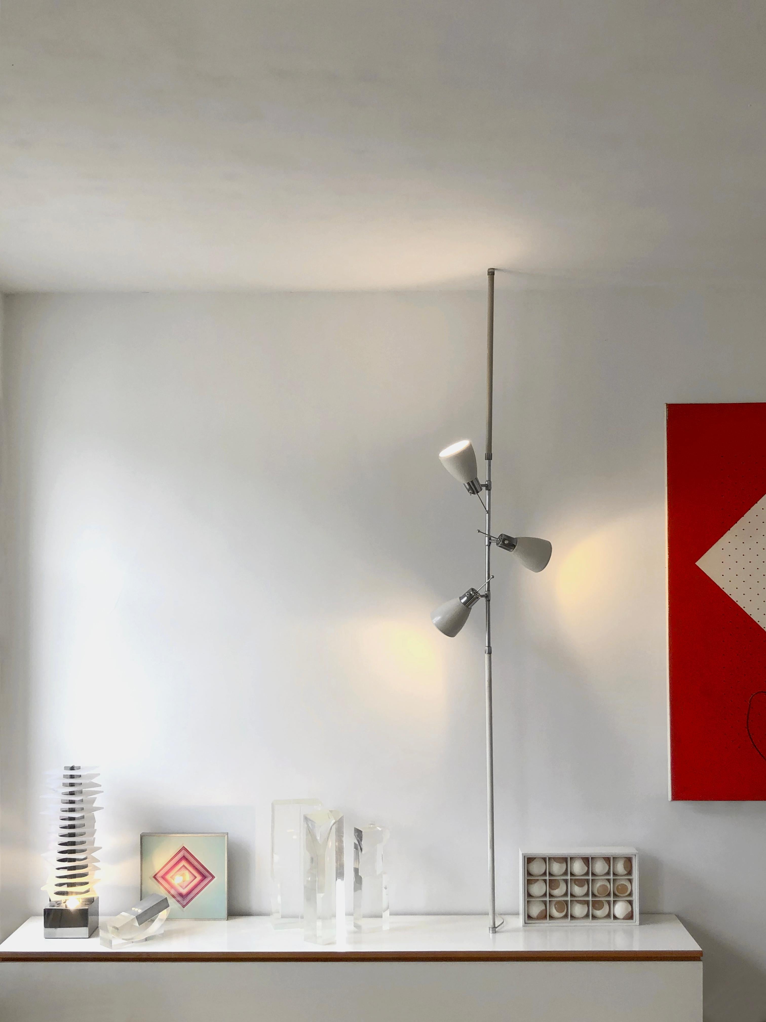 A mid-century-modern space-age, telescopic floor lamp, with 3 orientable lights, to be fixed by pressure between ground (or furniture) and ceiling, in a white laquer and chrome finish version, iconic model by Etienne Fermigier, produced by Monix,