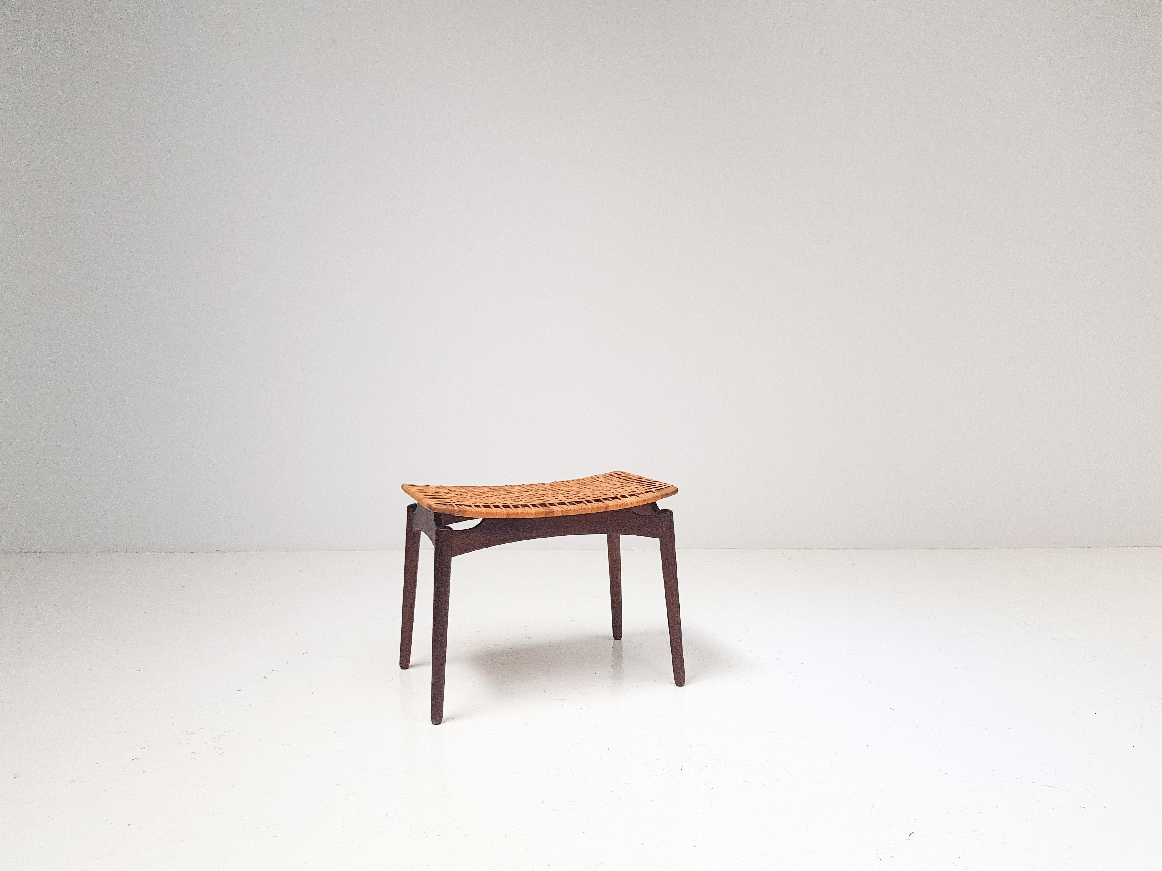 A woven cane and teak stool, by Olholm Denmark dating from the 1950s.

With tapered legs and having a curved woven seat it gives the stool a floating appearance and overall has a very elegant look.

The design is reminiscent of one by Finn