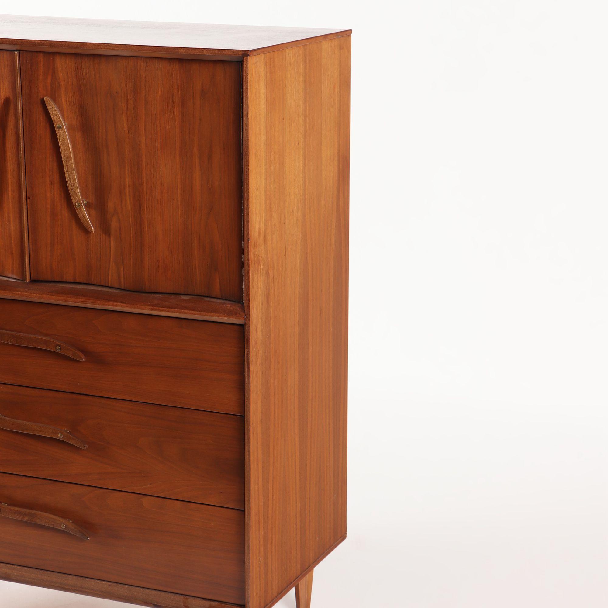 A Mid-Century Modern walnut dresser cabinet having sculptural door and drawer pulls circa 1960.