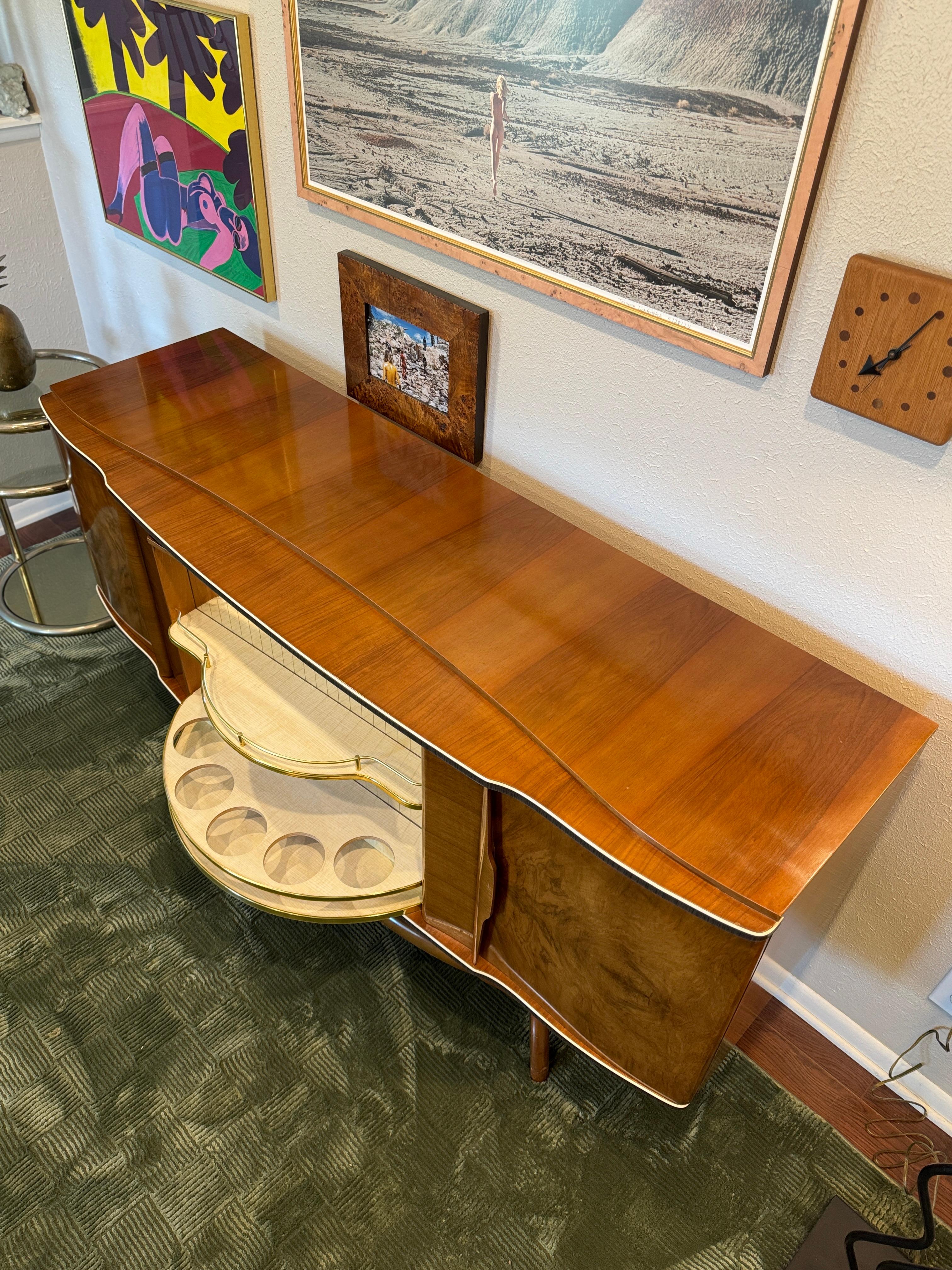 Eine atemberaubende trockene Bar, für echte Liebhaber! A 
nussbaumfurnierter Schrank von Beautility mit einer drehbaren Glasvitrine in der Mitte, die den Blick auf die dahinter liegende Bar freigibt, und zwei Schränken auf beiden Seiten. Um 1960er.