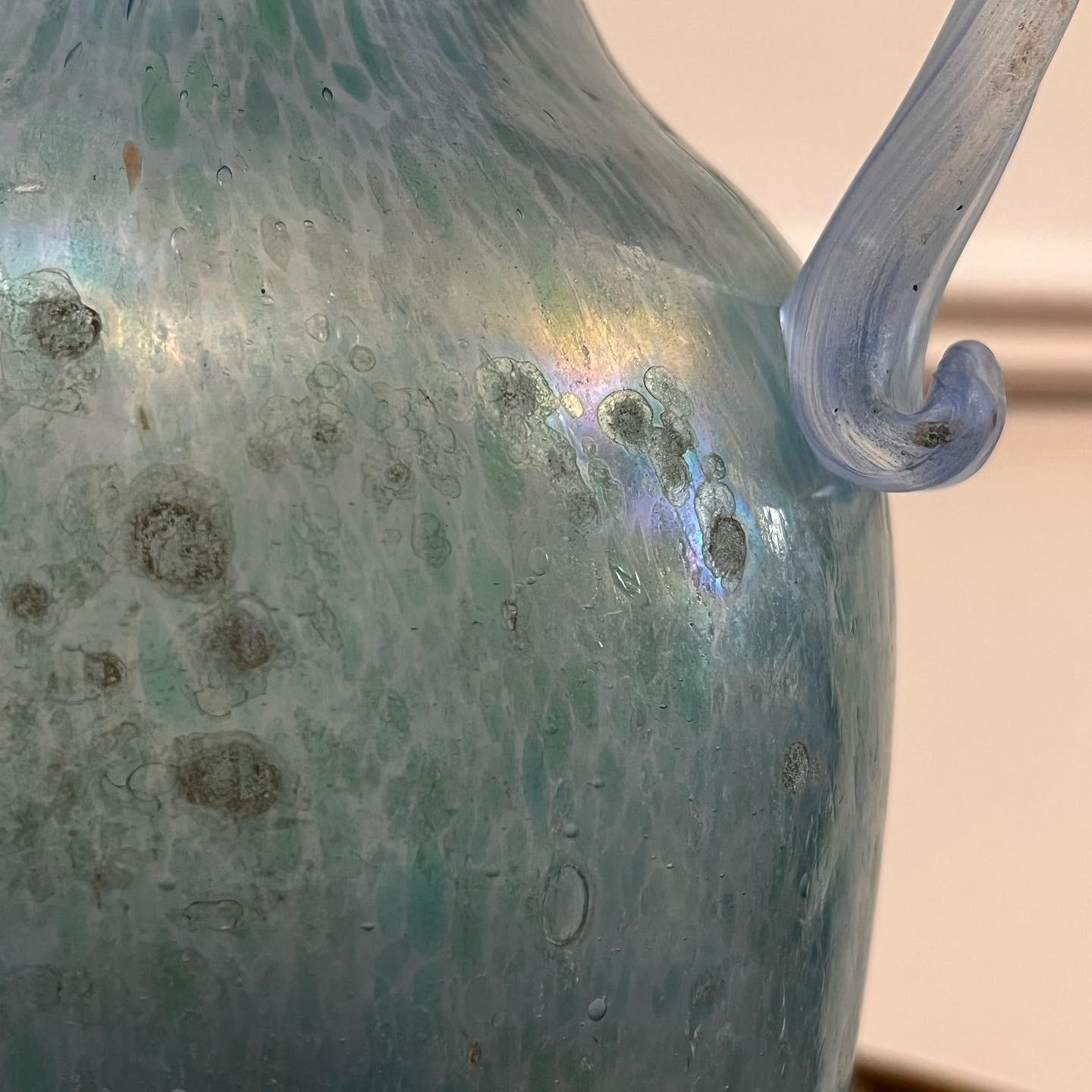 A twin handled murano glass vase in Roman blue, speckled with Venetian green and iridescent finish to surface, now mounted as a lamp. 

Italian, Mid Twentieth Century 

.
