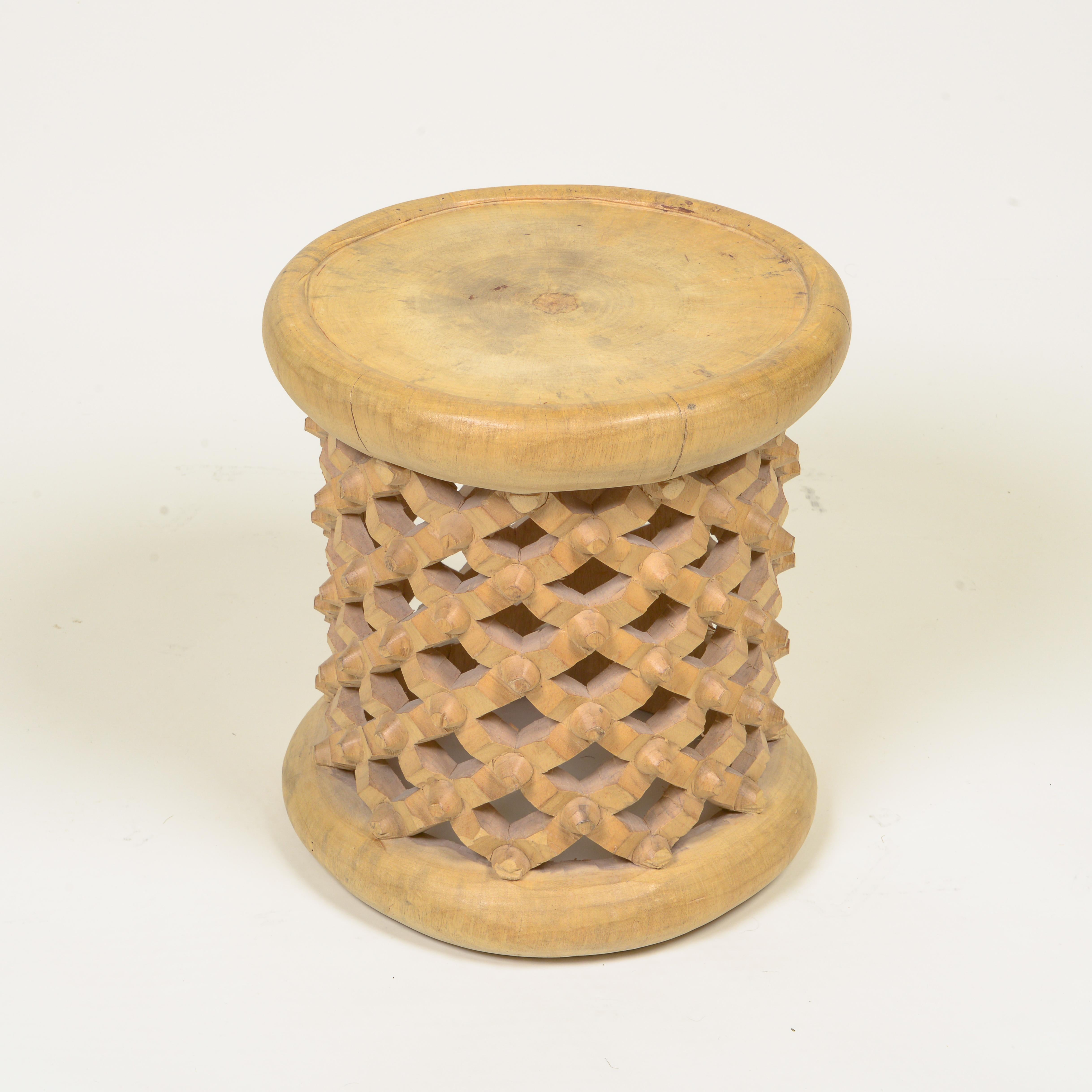 Hand-carved cylindrical Bamileke wood stool with traditional intricate lattice pattern.
