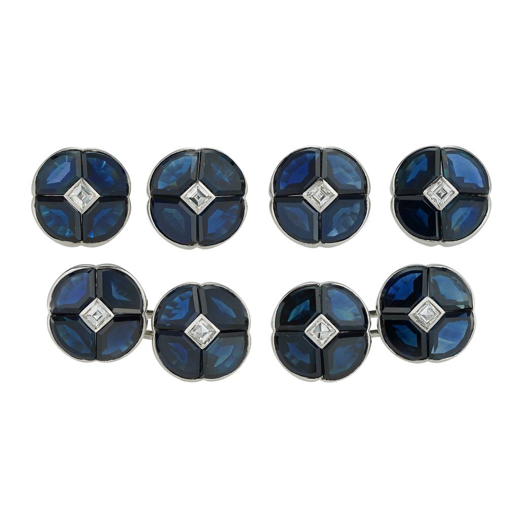 A mid-century sapphire and diamond dress-set, consisting of a pair of cufflinks and four buttons, each with a quatrefoil design, centrally set with a carré-cut diamond surrounded by four calibré-cut sapphires, the diamonds estimated to weigh 1.2