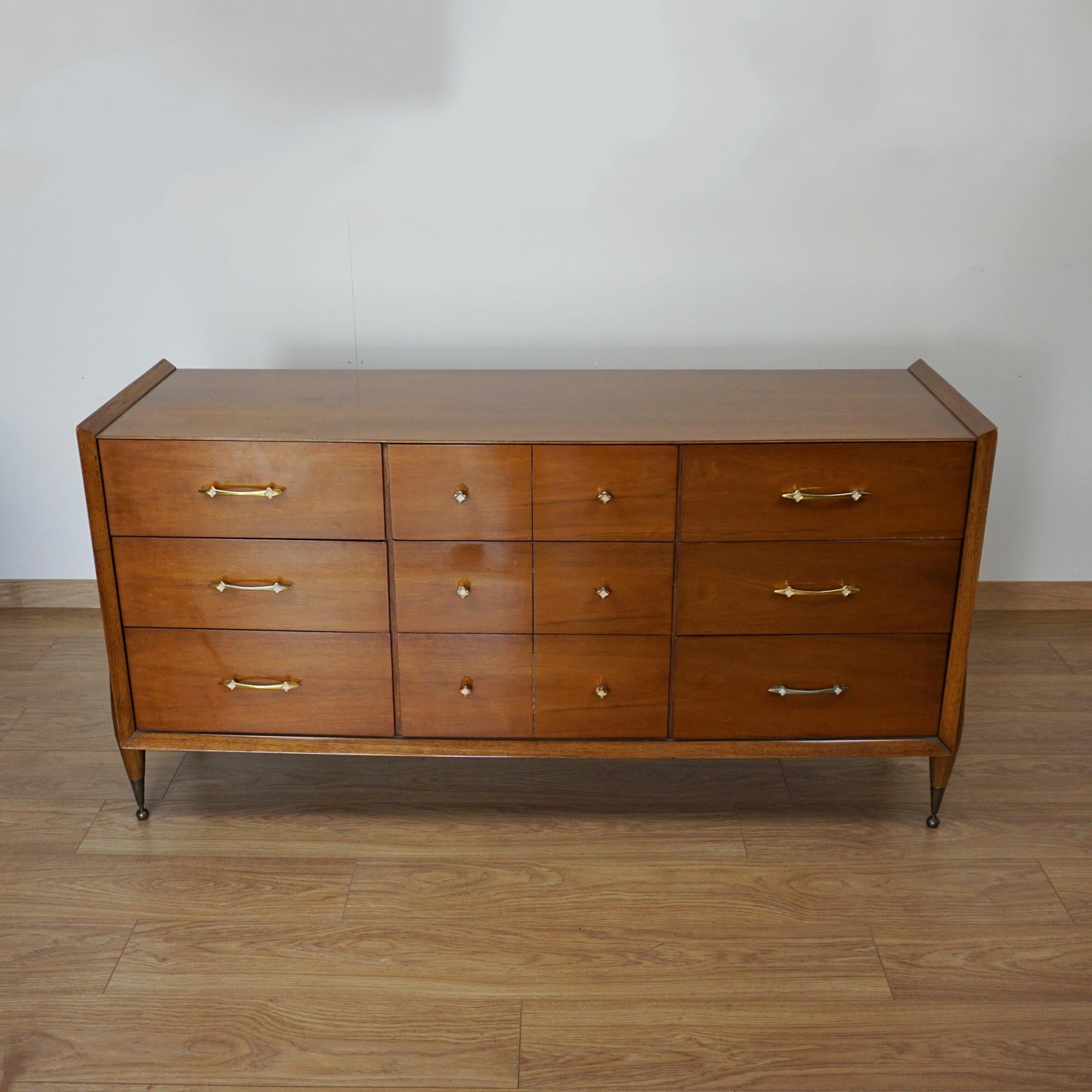 A mid-century Sideboard designed by Kent Coffey for J.B. Van Sciver Co. Atomic shaped legs with brass capped feet. Walnut veneered throughout with original brass and mother of pearl handles. Makers label to inside of top left drawer. 

Dimensions: H