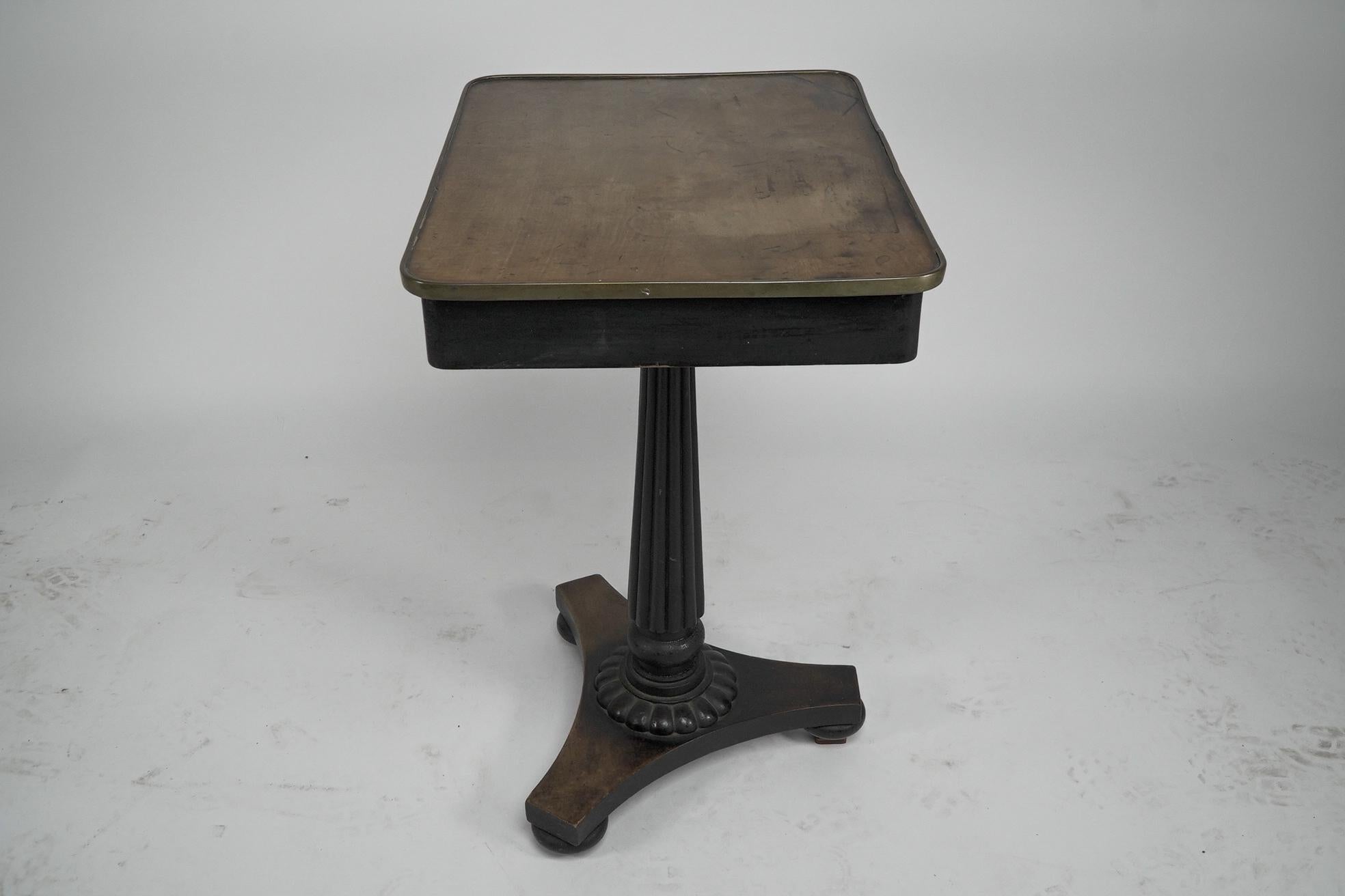 An early to mid-Victorian mahogany and satinwood top single drawer pedestal occasional table. A brass edge to the satinwood top and a brass pull handle with a floral backplate to the drawer, raised on a single tapering fluted upright pillar with a
