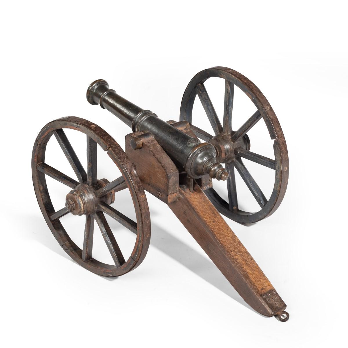 A mid-Victorian model of a field cannon, the bronze barrel set on an oak carriage with large iron-bound wheels, with traces of the original black, red and white paint. English, circa 1875.