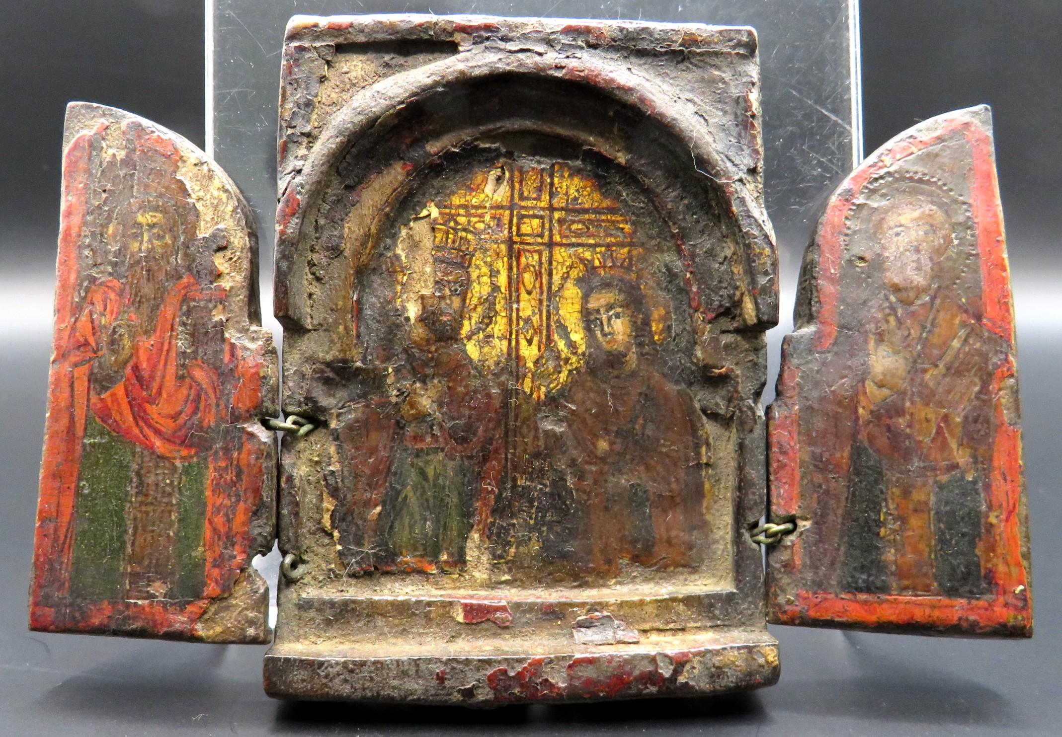 A rare miniature Greek Ottoman Period (1453-1821) hand painted icon triptych. The diminutive hand carved wooden case affixed with a pair of conforming hinged panels, opening to reveal an arched niche centred by hand painted images executed in