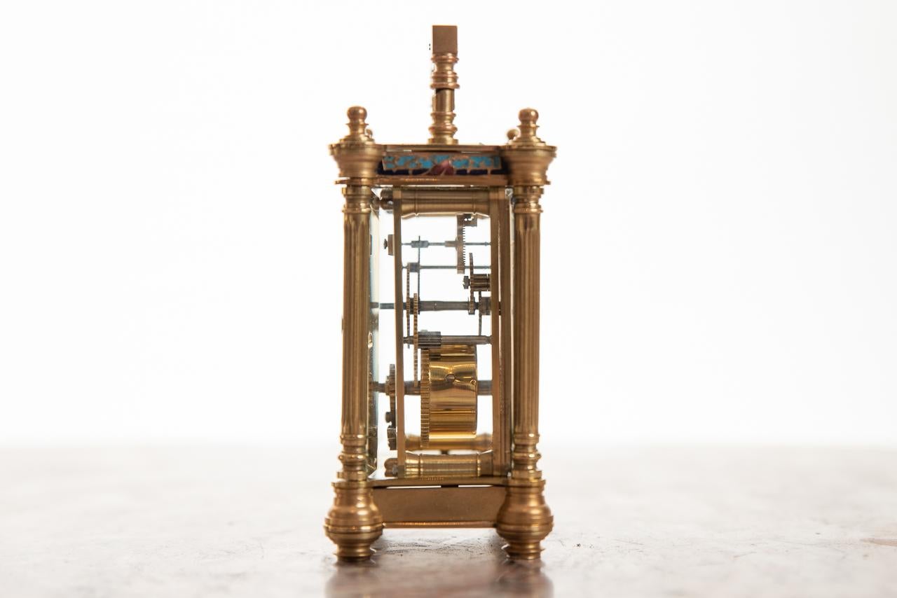 A very fine 8 day French timepiece brass/champlevé carriage clock with columns to all four corners and decorative handle. 
All four sides decorated with champlevé enamel. 
A very small example, which is very hard to find,
circa 1895.