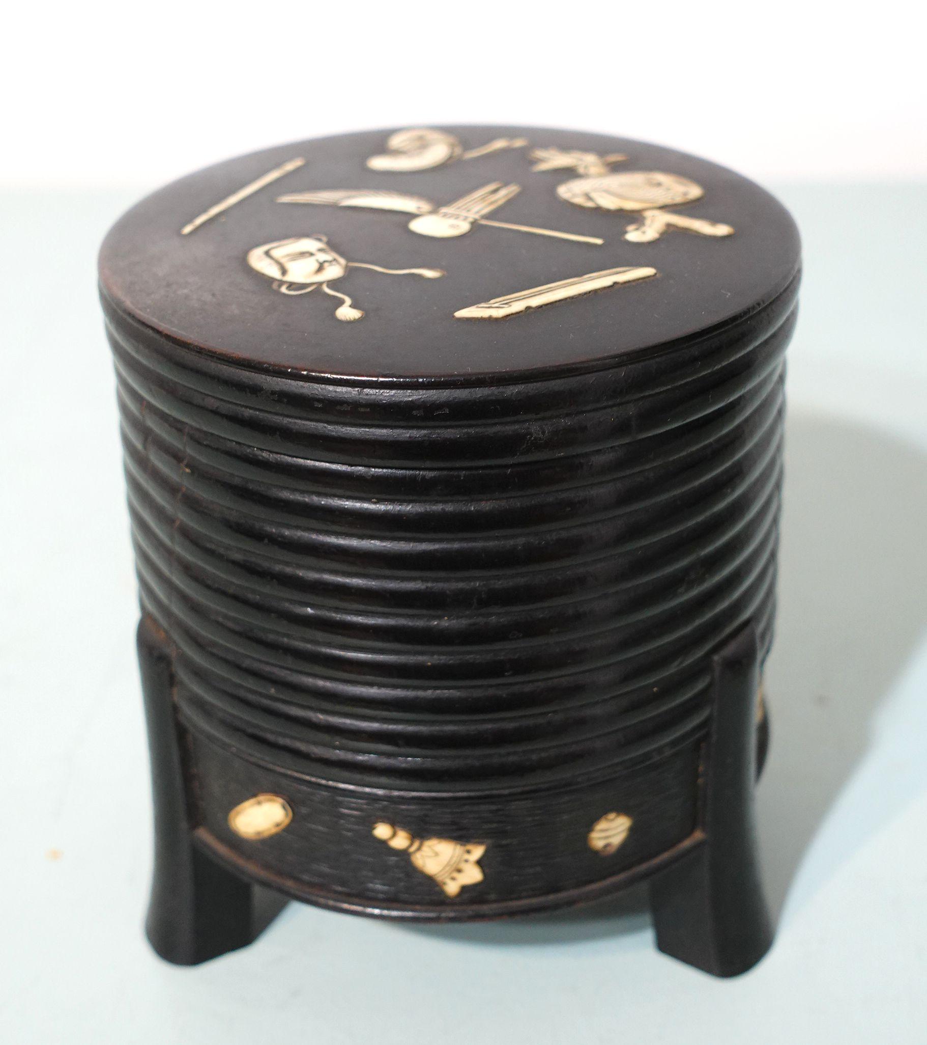 A Meiji period a miniature carved ebony hokkai decorated with lots of inlaid elements on the lower band and on the fitted lid and resting on three feet. one small inlay object missing see photo #6, lower right corner.