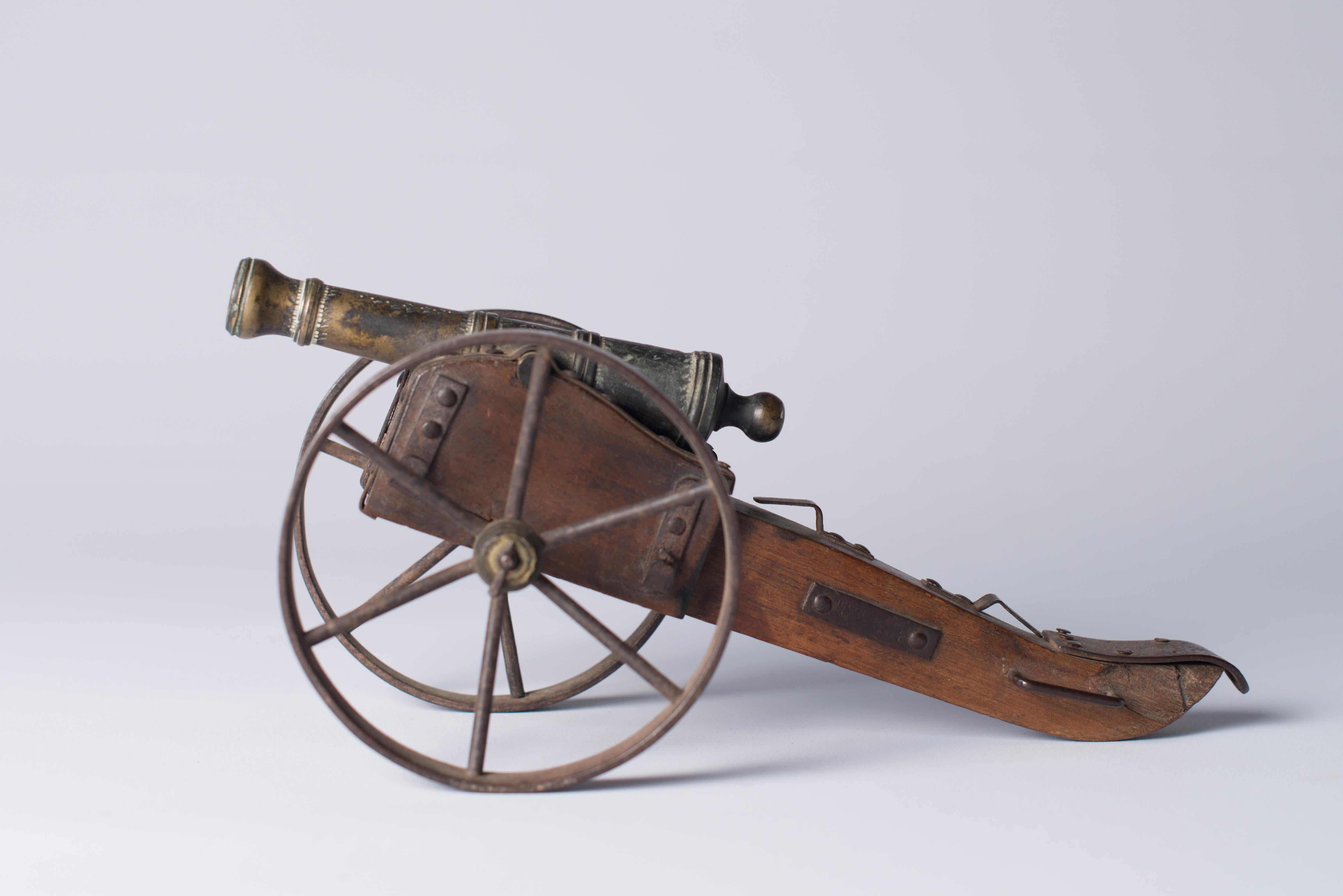 A miniature patinated bronze canon on a wood field gun-carriage with two openwork iron wheels and mounts, 19th century.

Marked ‘le Foudroyant’, literally: 
