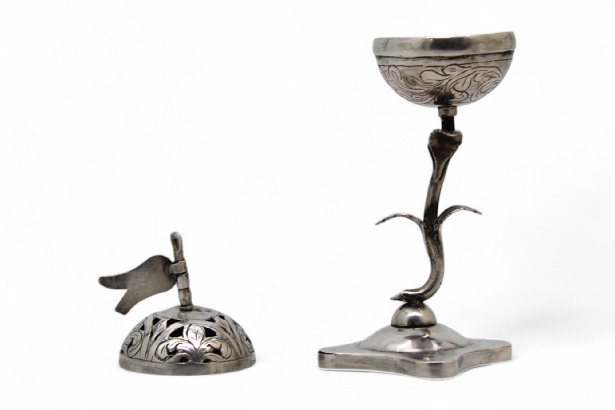 This exquisite early 19th-century silver spice container, crafted in the Poland–Ukraine region around 1830, is a remarkable example of miniature Judaica infused with refined naturalism and delicate symbolism.

The container rests upon a finely
