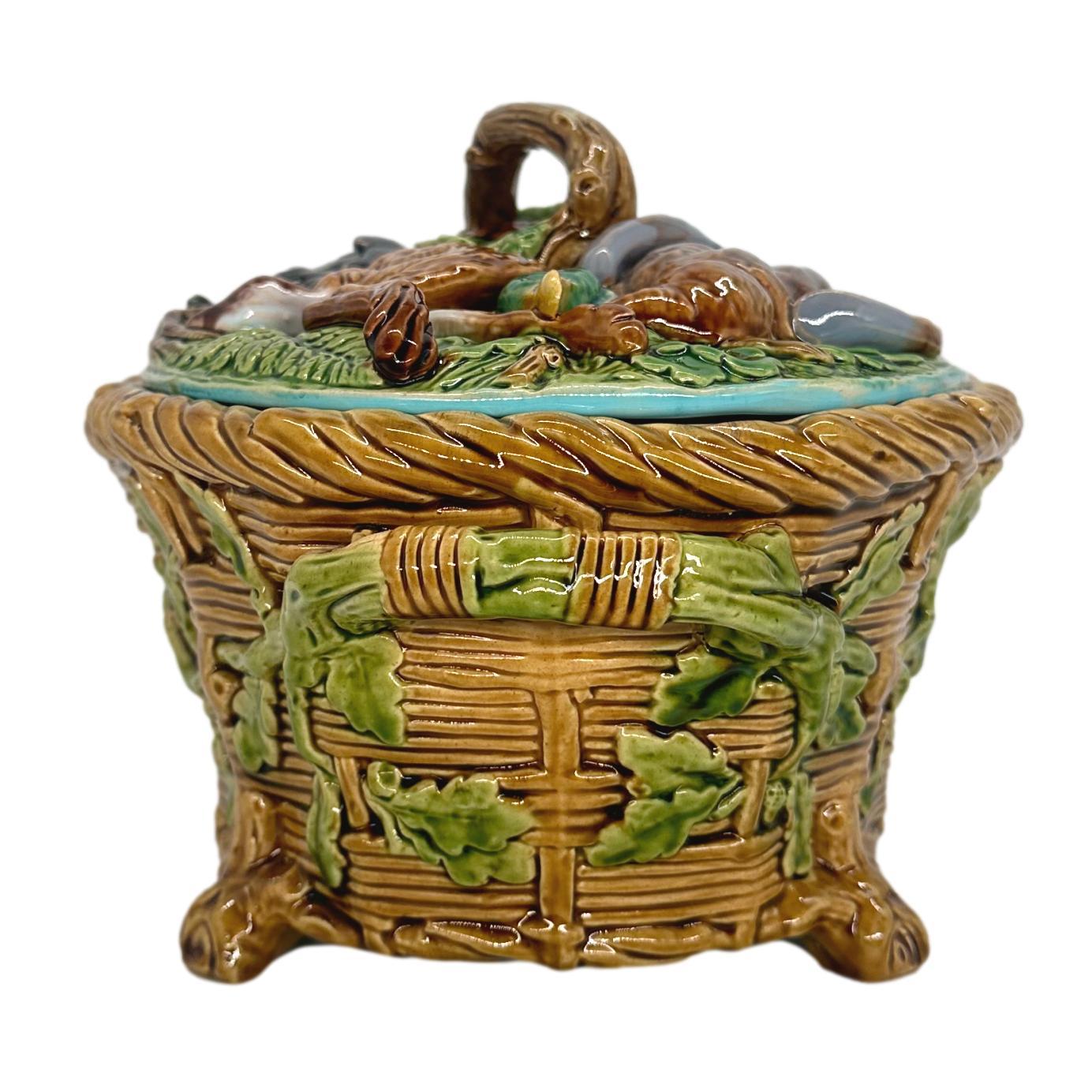 Minton Majolica Game Pie Tureen, Cover, and Liner, la base moulée comme un panier en osier avec des feuilles de chêne émaillées vertes et des poignées de branches bandées sur des pieds surélevés, le couvercle avec du gibier moulé en haut-relief : un
