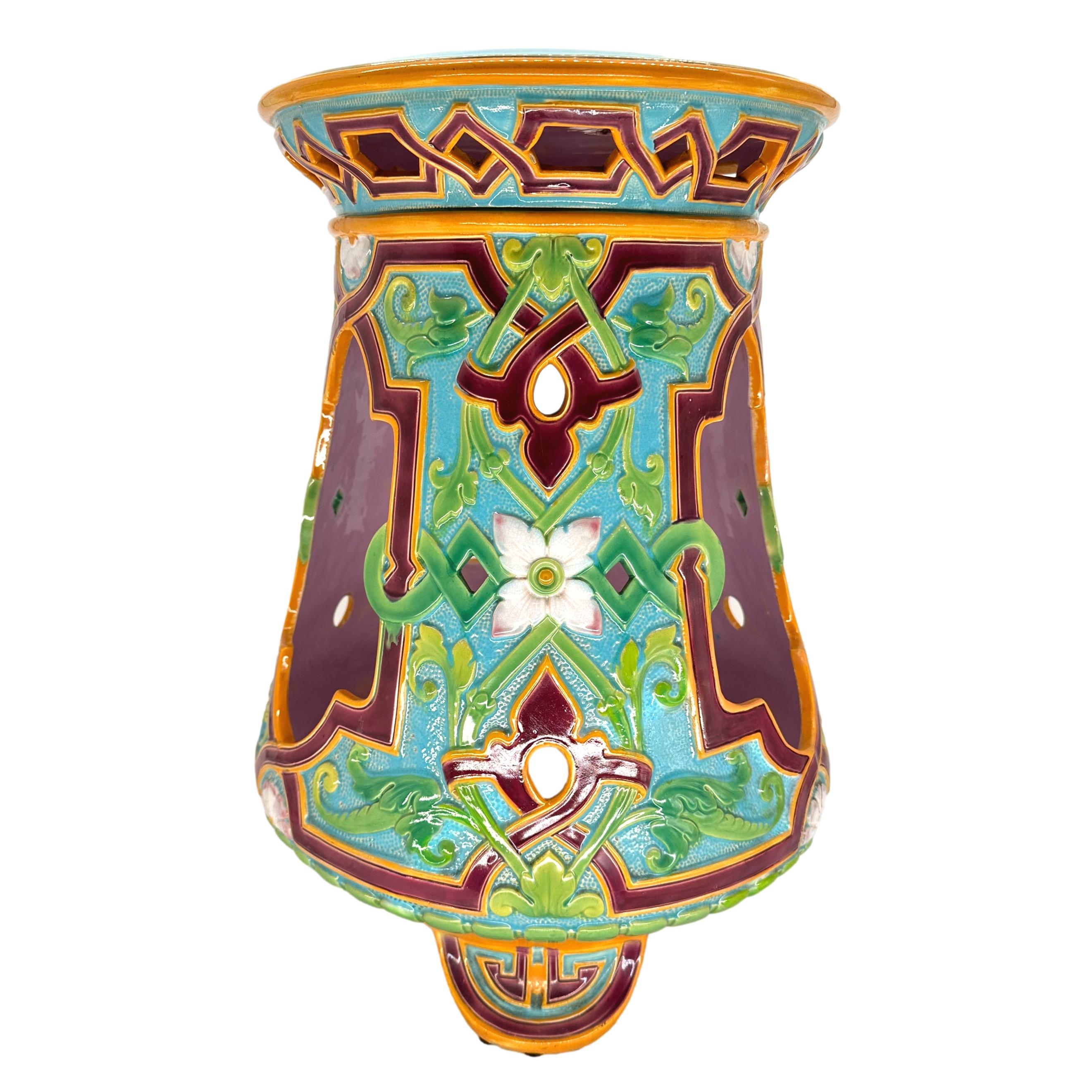 A Minton Majolica Moorish-Style Pierced Garden Seat of Geometric Pattern, with three shaped panels with relief-molded flowers, foliage, aubergine-glazed strapwork, with green and yellow on a turquoise-glazed ground, alternating with three open