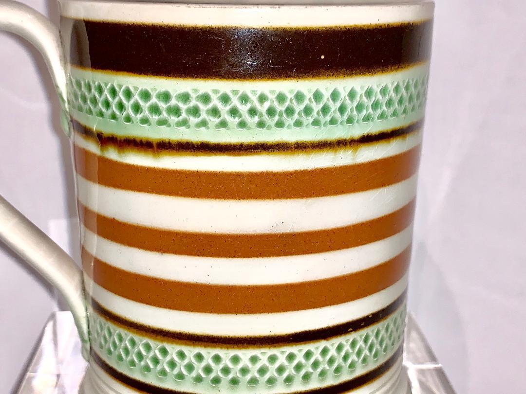 A Mochaware mug, England, circa 1810
Decorated with green glazed rouletting and light and midnight brown bands of slip.
Dimensions: Diameter 3