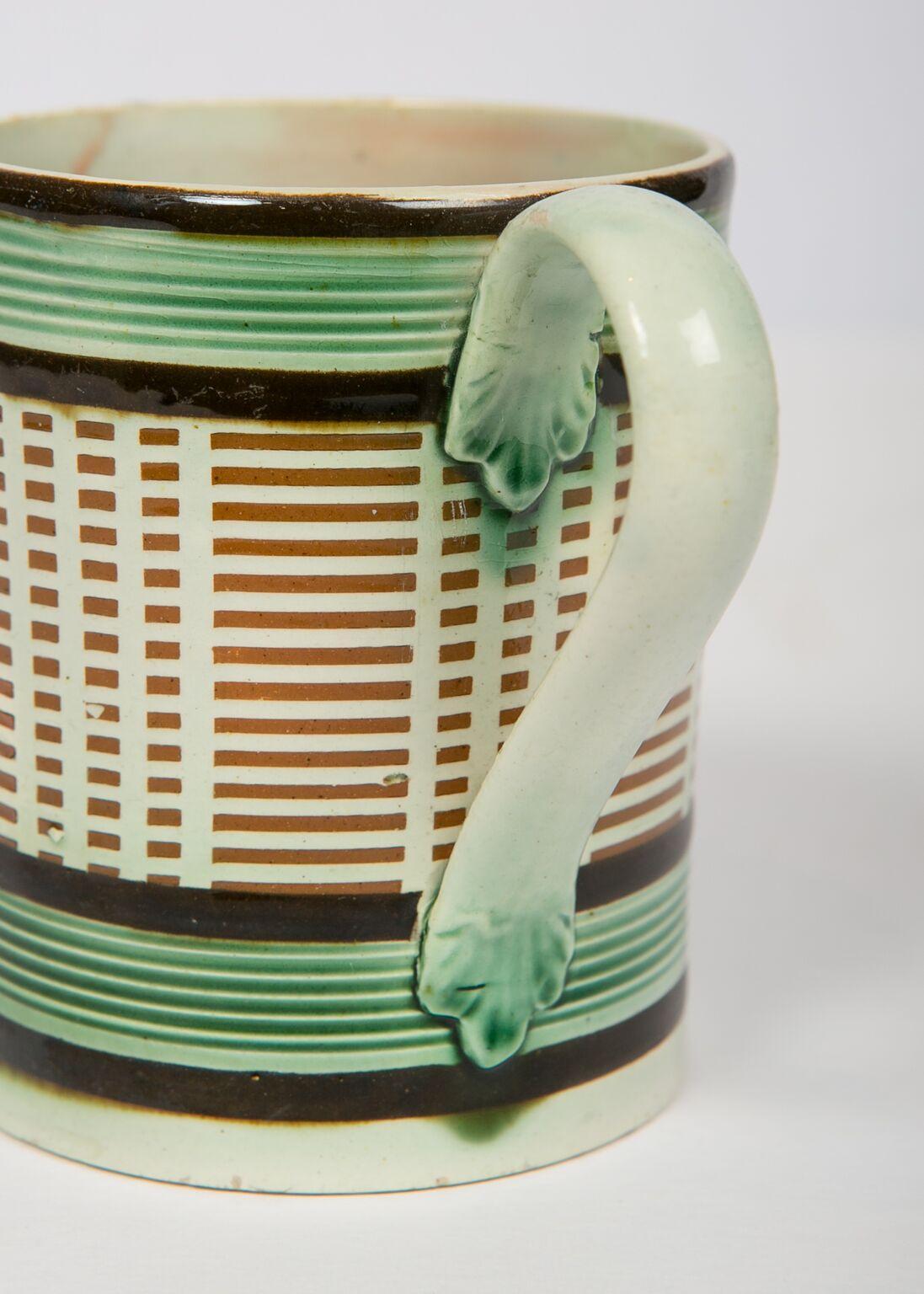 A Mochaware mug, England, circa 1815
Decorated with green glazed reeded bands, midnight brown slip bands and inlaid light brown long and short engine-turned slip lines.
Dimensions: Diameter 3