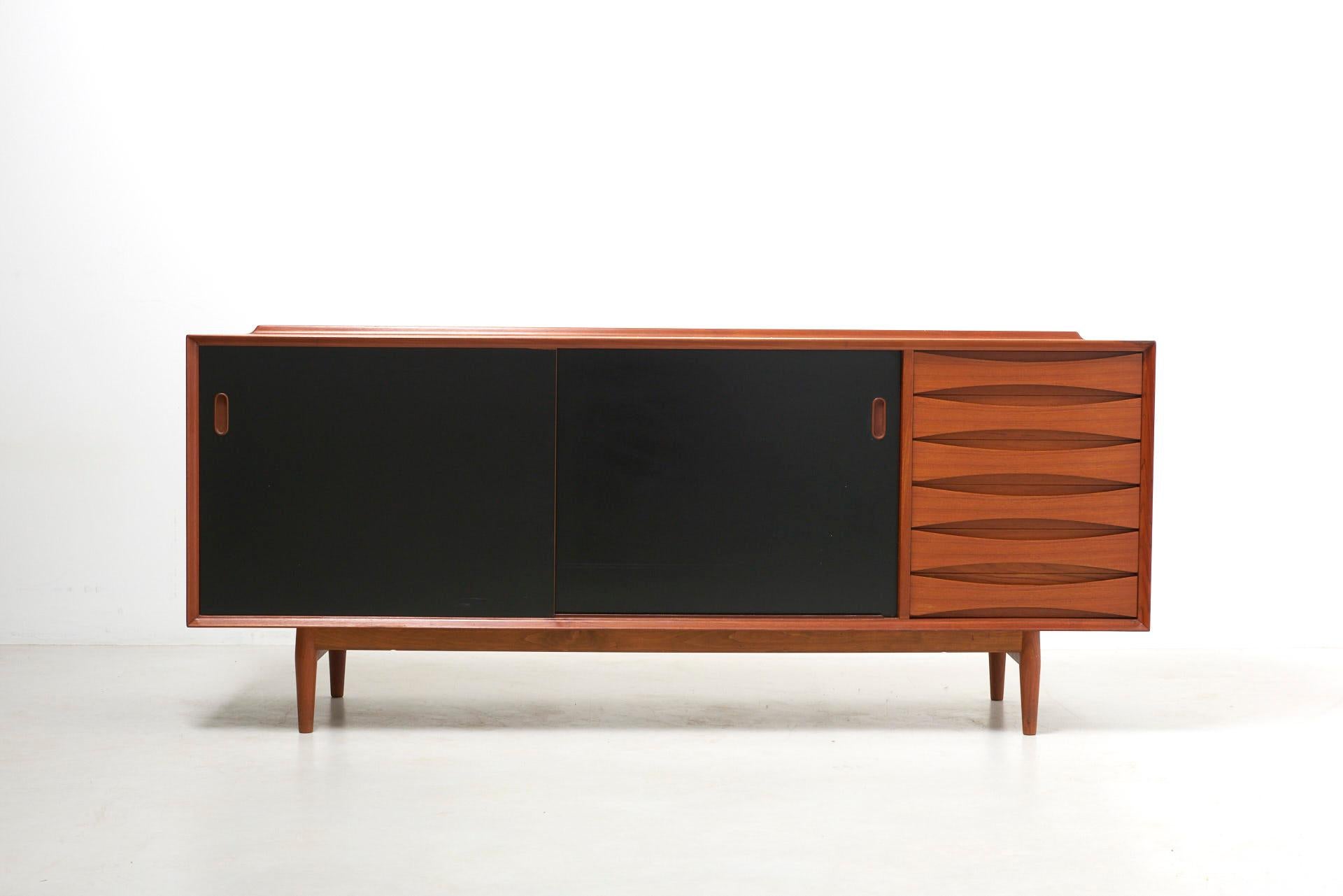 A sideboard in teak with 2 reversible sliding doors (black or teak), designed by Arne Vodder for Sibast Furniture. Features the typical raised edge and curved drawers, both a signature of the designer.
Made in Denmark.