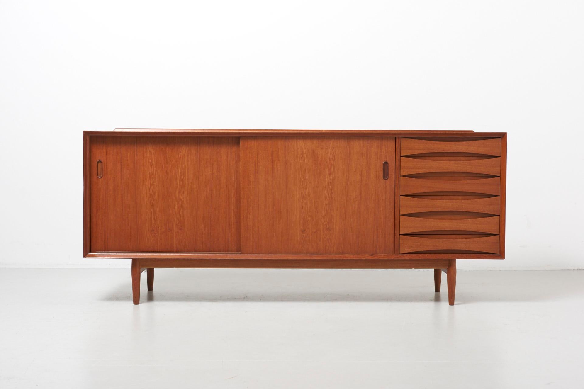 Sideboard in teak with 2 reversible sliding doors (black or teak), designed by Arne Vodder for Sibast Furniture. Features the typical raised edge and curved drawers, both a signature of the designer.
Made in Denmark.