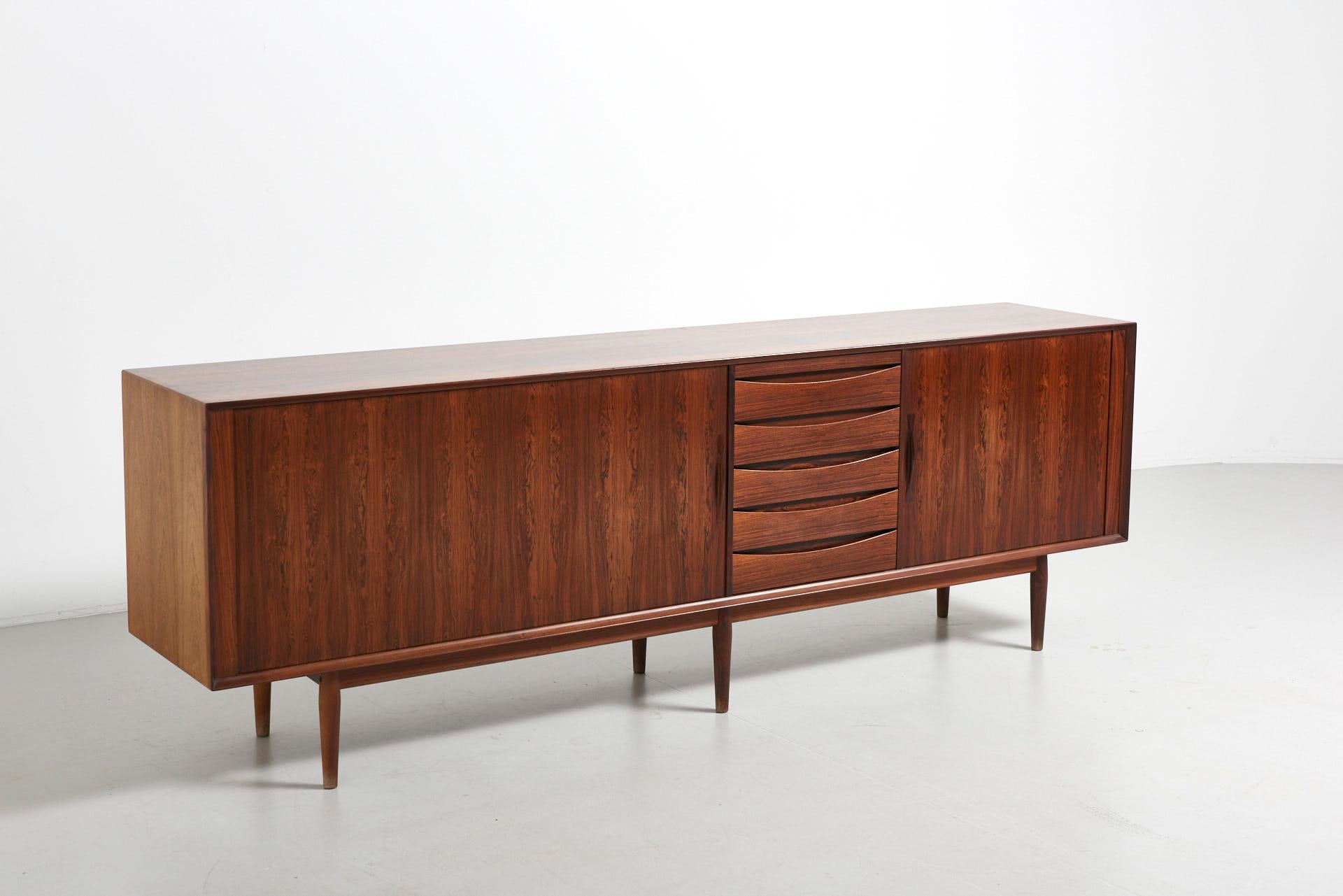 A rare sideboard, Model 76 designed by Arne Vodder in the 1950s. It features tambour doors, drawers and a tray in black leather. In a very good condition, with normal traces of use and one side slightly faded through sunlight. Made by Sibast