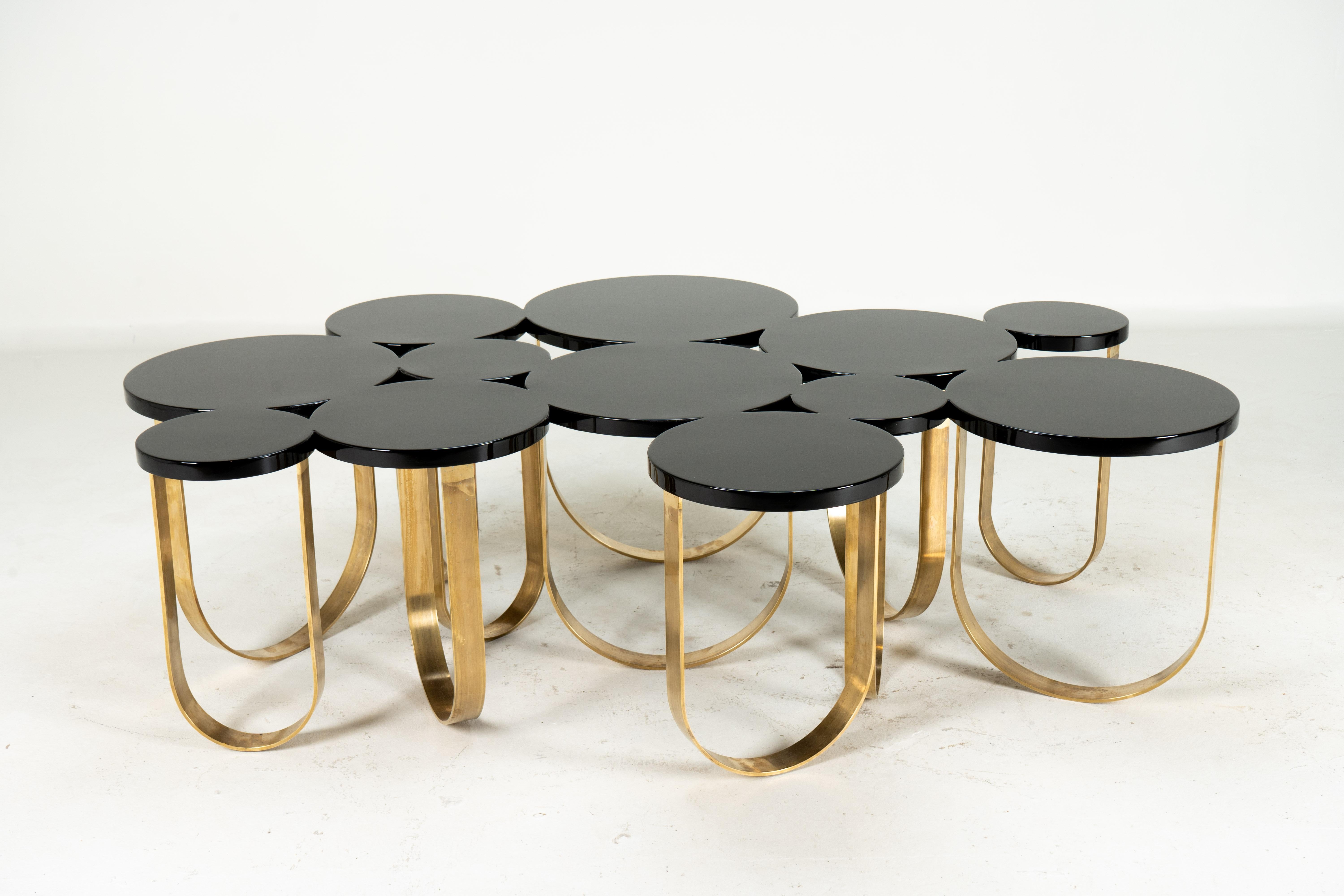 This unusual coffee table combines a top made of black-lacquered wood discs and a complex brass loop base. The top is made from a solid wood that has been laser-cut to resemble individual discs; in fact, they are one. The substrate was then covered