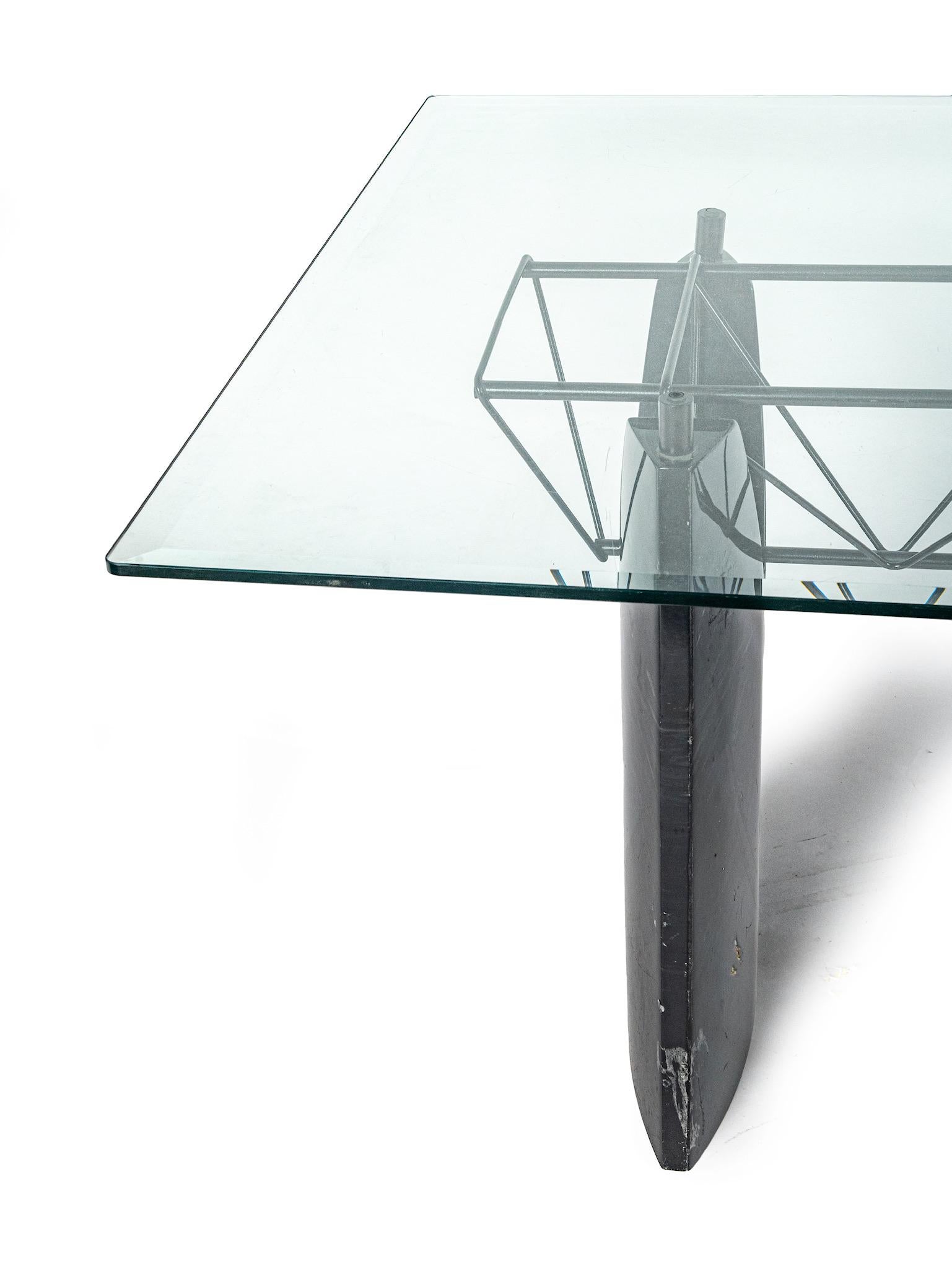 A modern rectangular dining table with black travertine base and glass top.