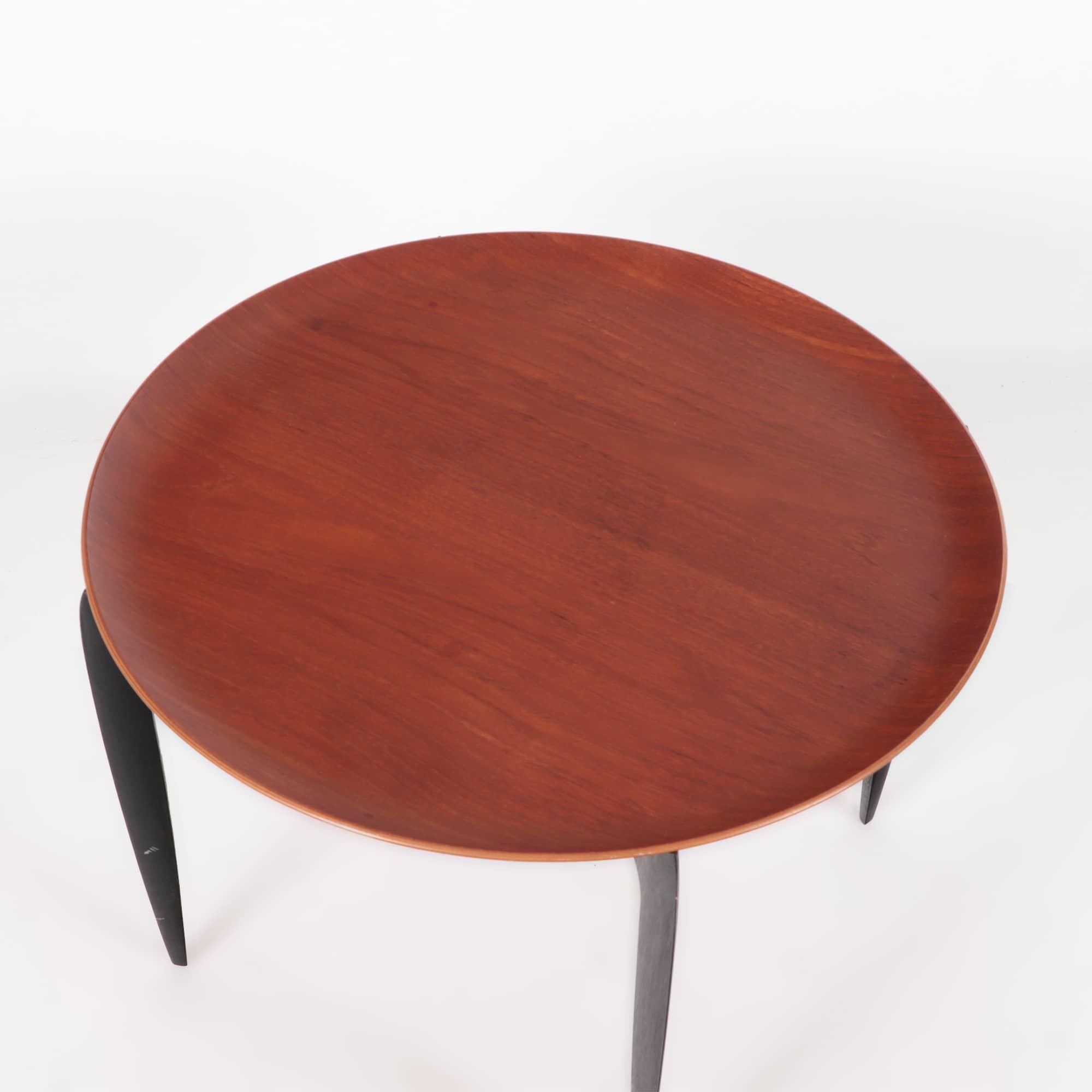 A Mid-Century Modern Engholm & Willumsen for Fritz Hansen teak tray table with circular dish form top and folding base circa 1960. The free standing tray top resting on black lacquered folding base. Marked on underside.