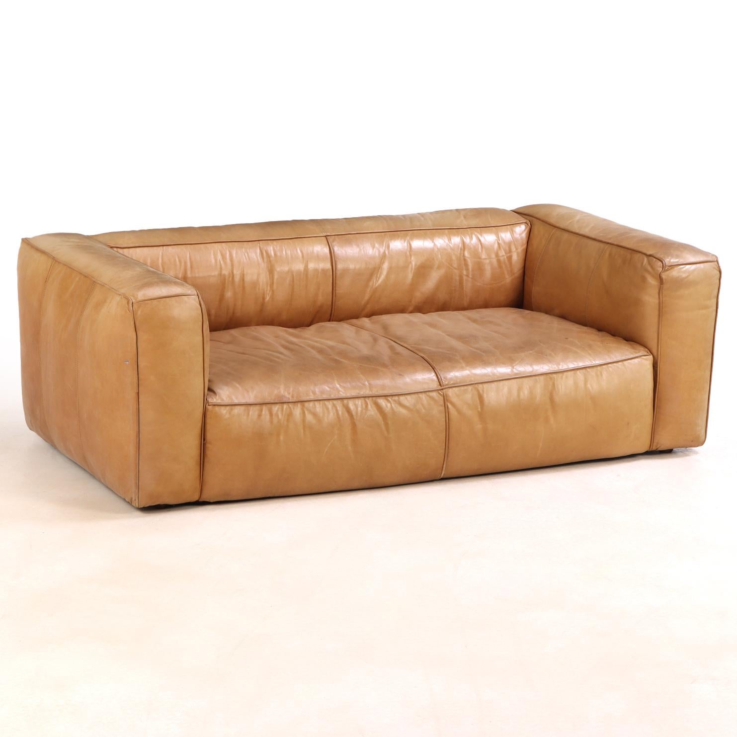 This striking French leather sofa makes a lasting impression with its clean, minimalist design. Featuring a straight low back and wide, square arms, it beautifully fuses mid-century modern sensibility with vintage charm. Upholstered in rich, supple