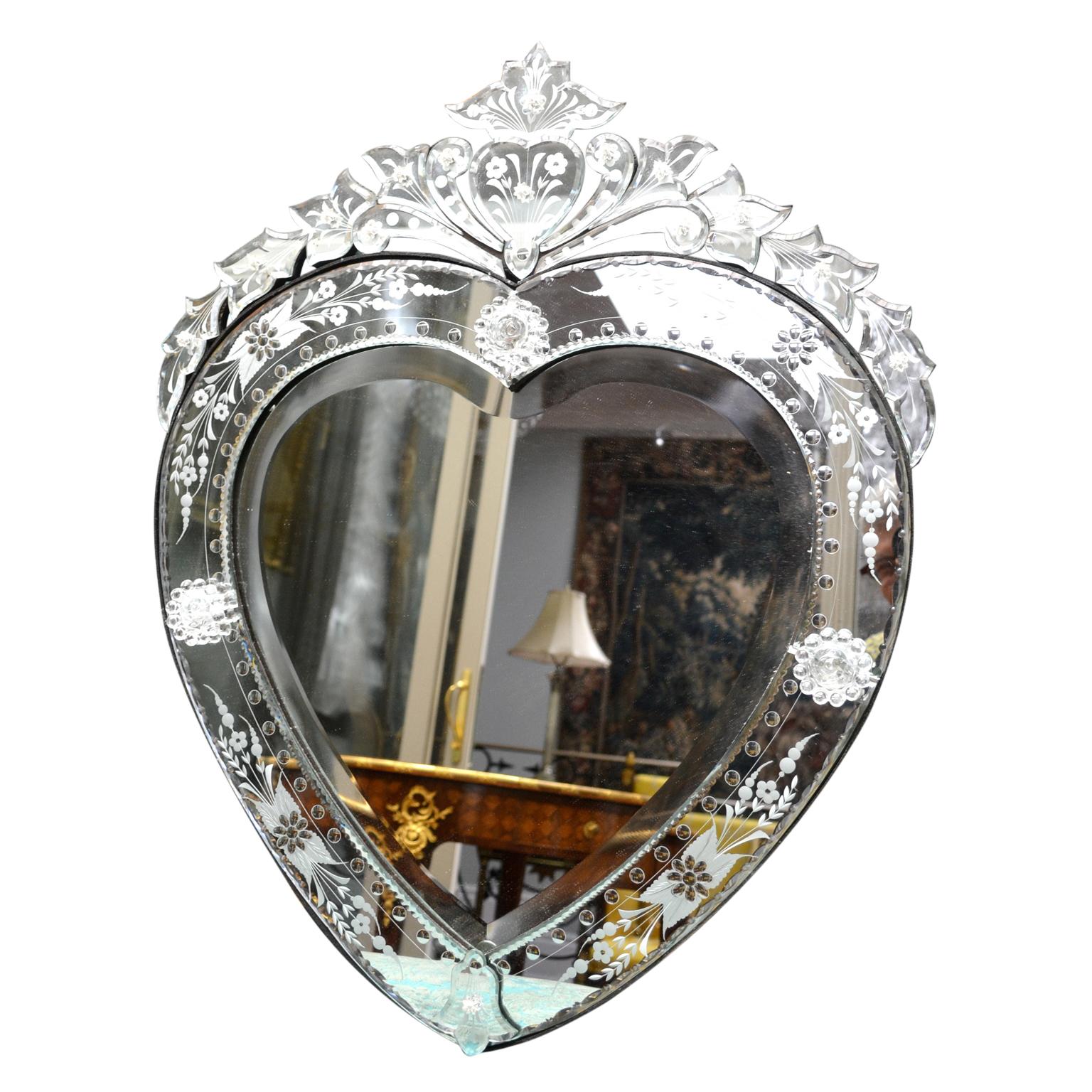 A decorative heart shaped Venetian beveled glass mirror with an edged glass border and domed top.
