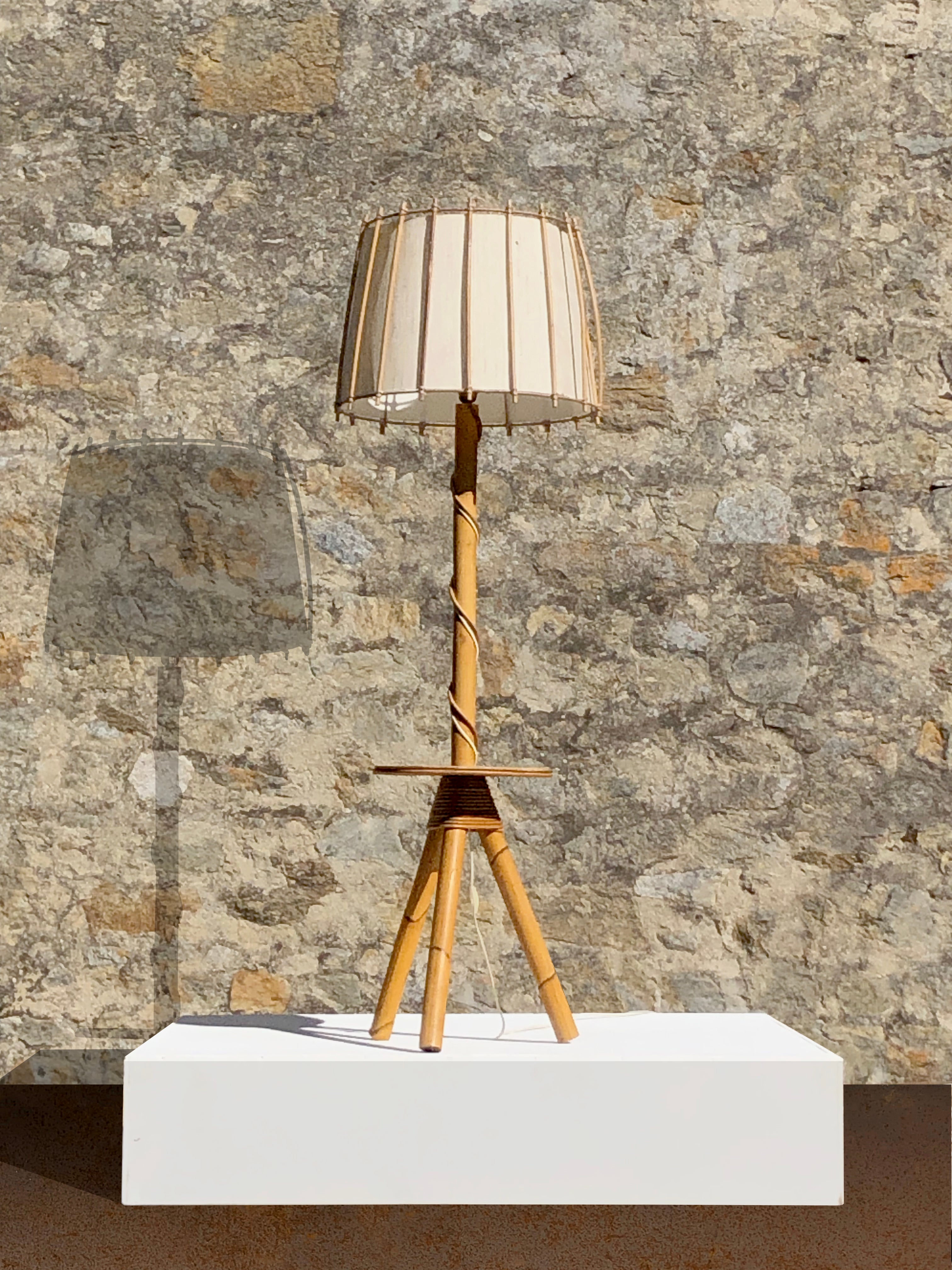 Un'affascinante lampada da terra a treppiede, Modernista, Rustico Moderno, Brutalista, anni '50, rigorosa base a treppiede e asse verticale in bambù, piano circolare in vimini verniciato, paralume in tessuto bianco sporco in una struttura in vimini,