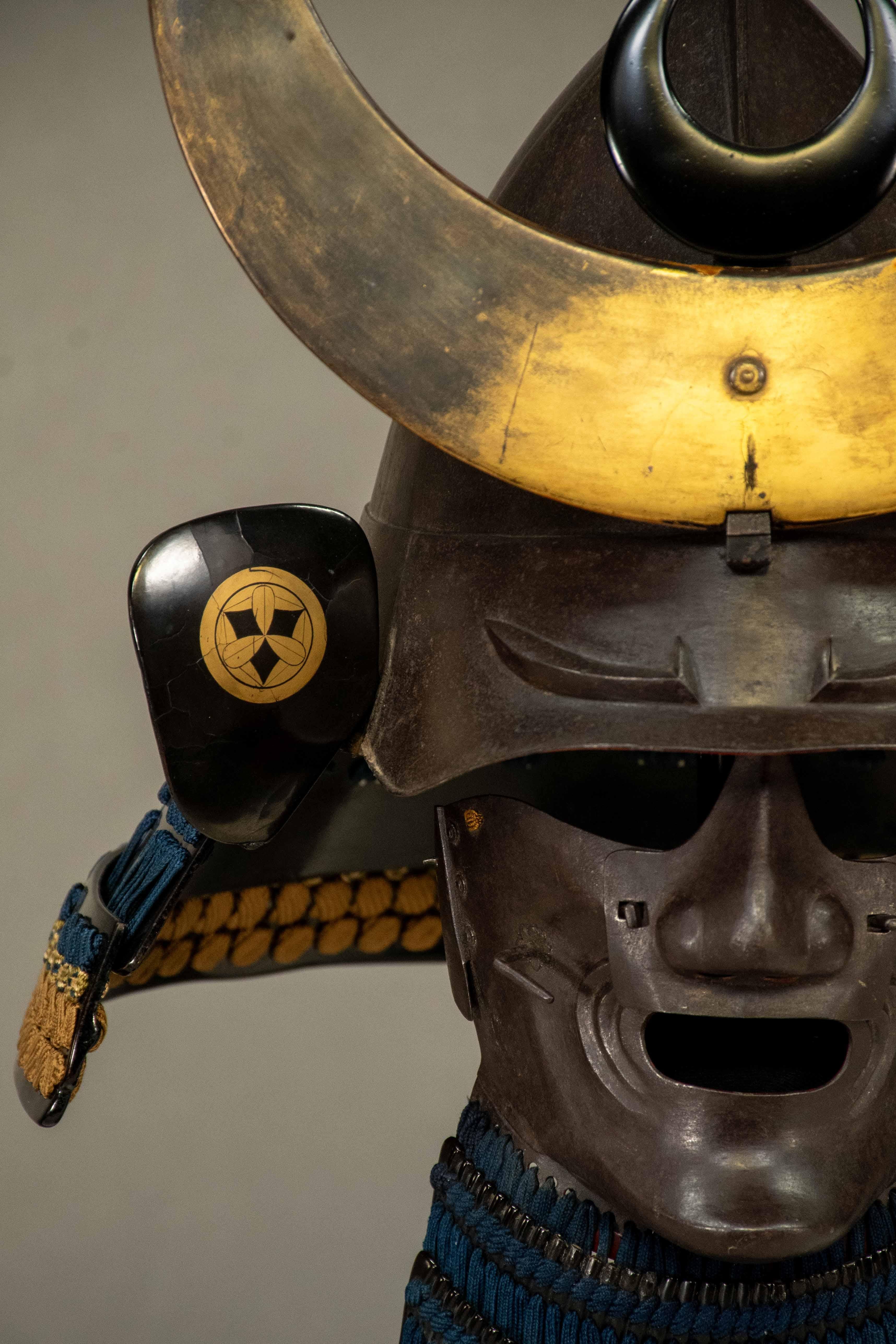 A Kabuto Momonari-type samurai helmet, so named because of its characteristic shape resembling a peach, made of natural iron. 

The visor (mabizashi) is embellished with raised eyebrows, while the front decoration (maedate), features an elegant gold
