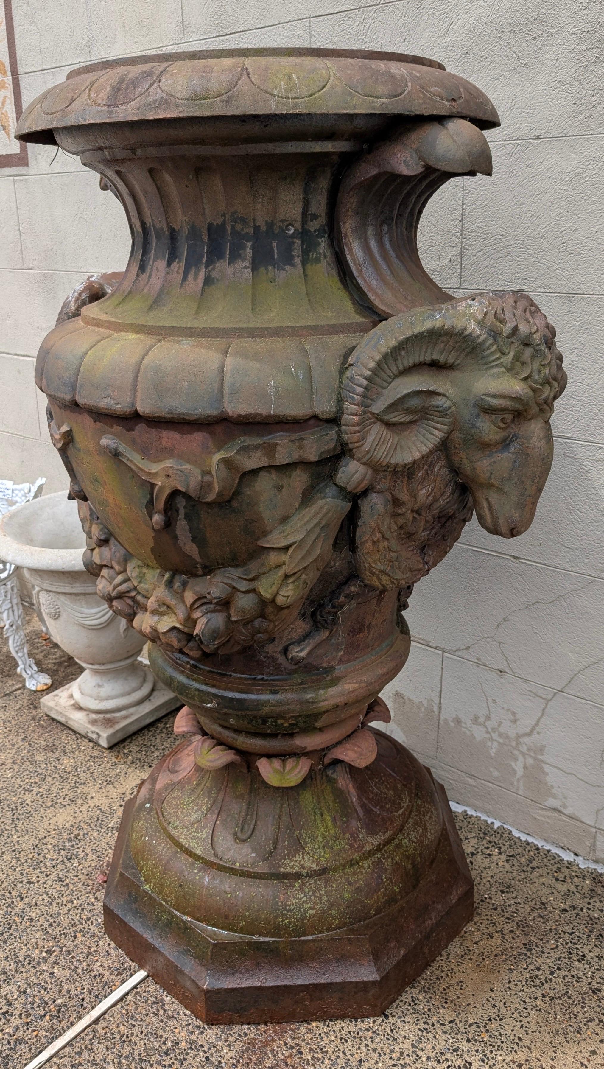 A monumental Antique cast iron garden urn with rams head sides.  The very large urn with original weathered surface originally from a Princeton New Jersey estate.  69 inches tall, very heavy