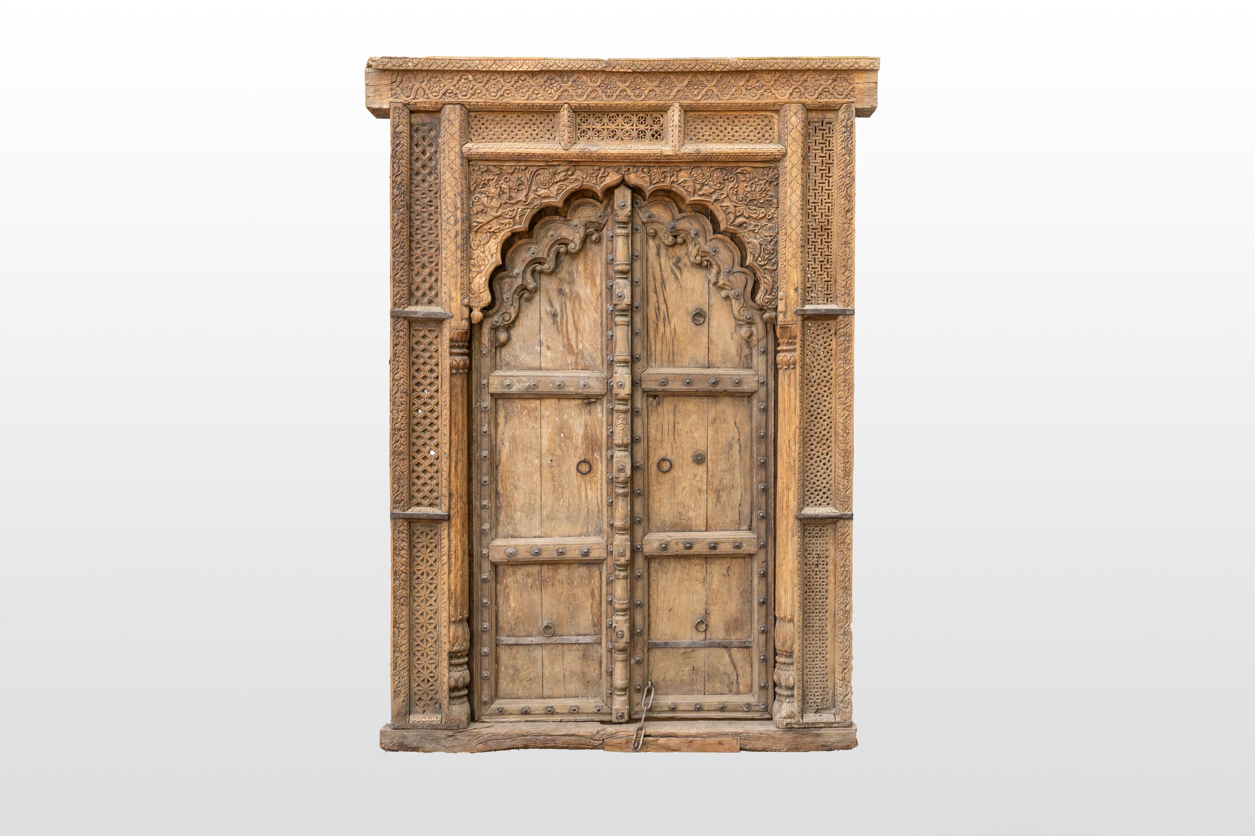 Esta original puerta de entrada de madera de sheesham, que data de la década de 1900, muestra la elegancia del diseño indo-sarraceno. Este amplio marco de puerta indio está dividido en secciones adornadas con intrincados motivos florales y