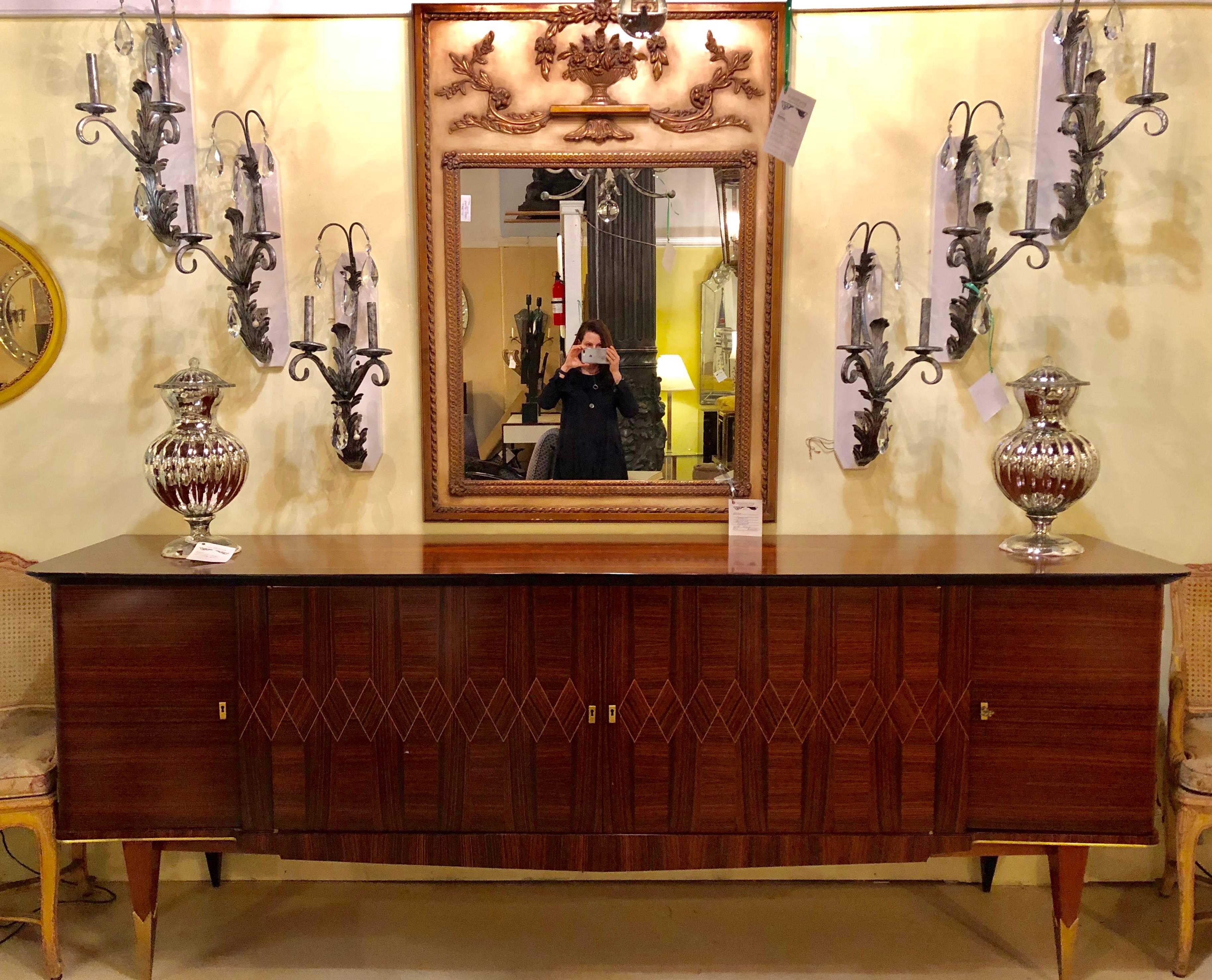 A monumental Art Deco Macassar inlaid sideboard or credenza with a full finished fitted interior having glass shelves. The tapering legs having bronze sabots with a full bronze framed undercarriage supporting a magnificent French deco case of finely