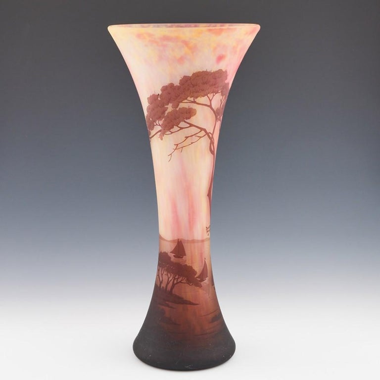 A monumental Daum landscape vase made c1905 in Nancy. A lakeland landscape is brilliantly depicted in mottled and striated primrose and raspberry coloured glass overlaid with chestnut acid cameo. This piece is signed Daum Nancy with the signature