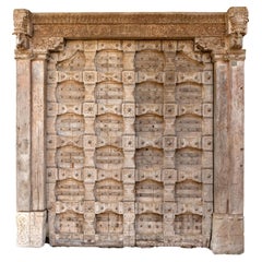 Una puerta artesonada india monumental con base de columna de piedra