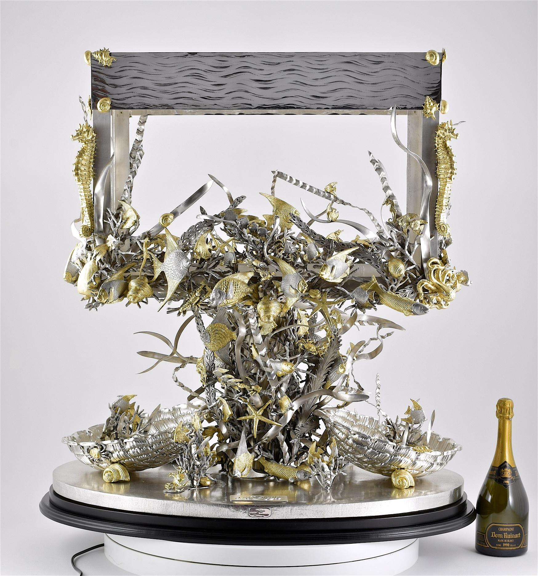 Unlike any piece that we have ever offered before, this monumental & heavy quality sterling silver aquarium is formed with an oval base mounted with two silver half-shells mounted with fish sea-foliage and crustaceans and fish, the central column