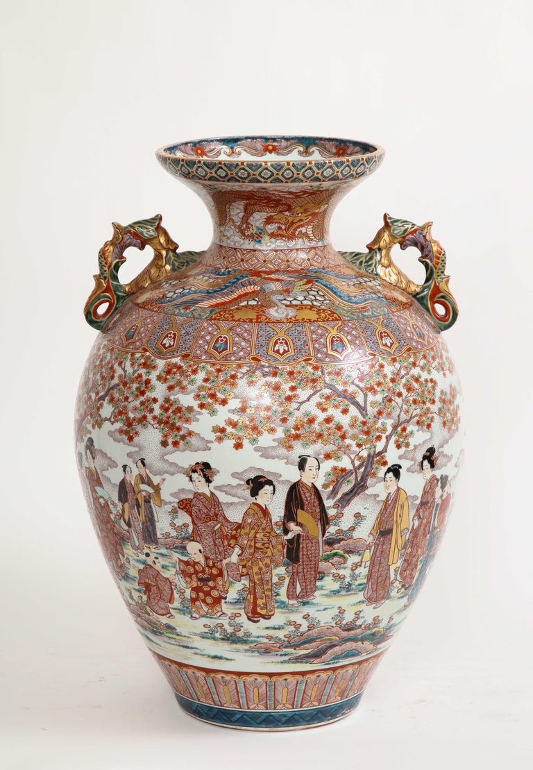 A Monumental Japanese Kutani porcelain vase, Meiji/Taisho Period, Signed Akiyama sei. The main body is all hand-painted with wonderful decorations which include Japanese figures of maidens, gentlemen, flowers, dragons, and looped porcelain handles.
