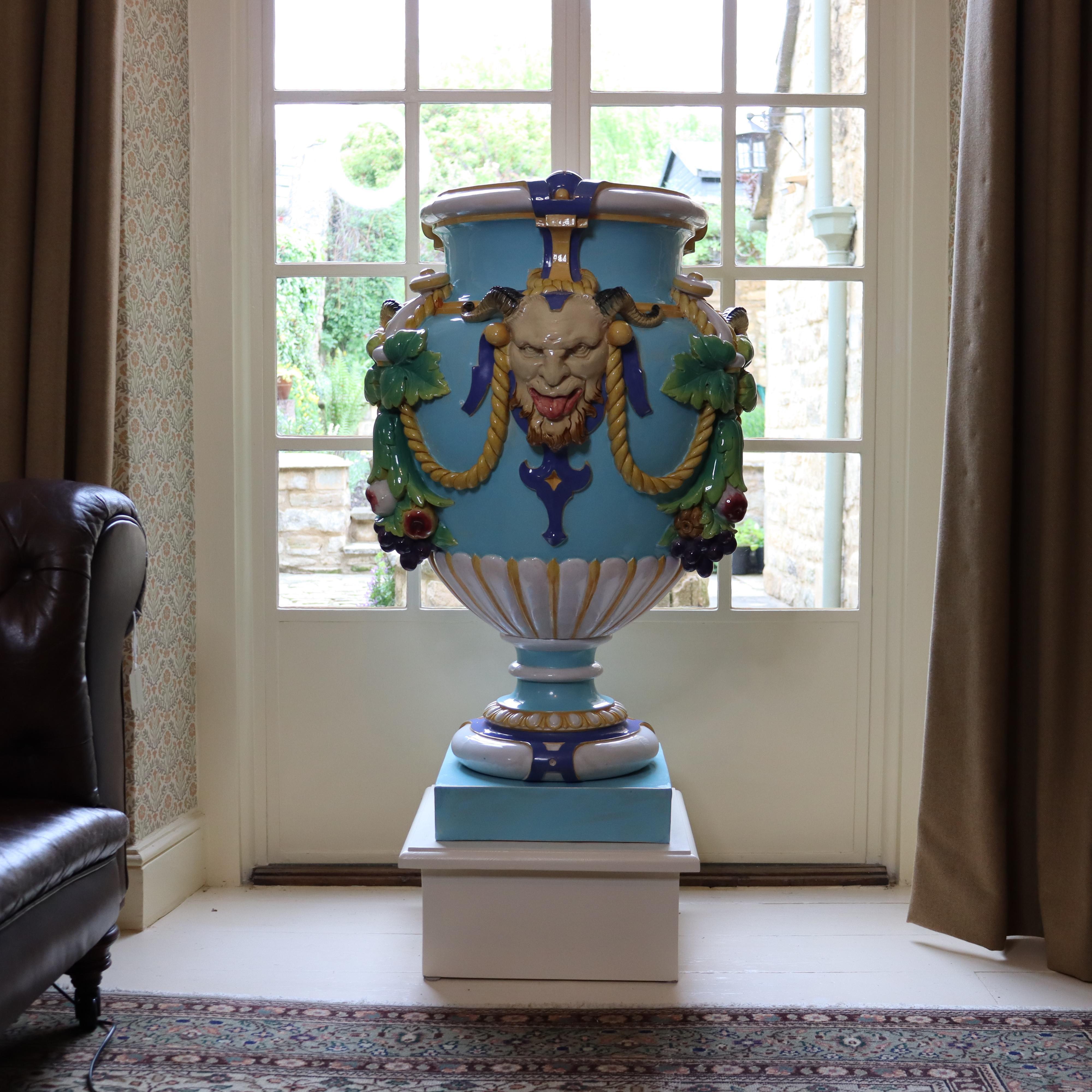 Vaso monumentale in maiolica di Minton a forma di urna, modellato e applicato con tre maschere di satiri 'Bacco' e festoni di frutta pendenti, su stelo e base a plinto. 

Uno dei risultati più significativi di Minton nel XIX secolo è stato lo