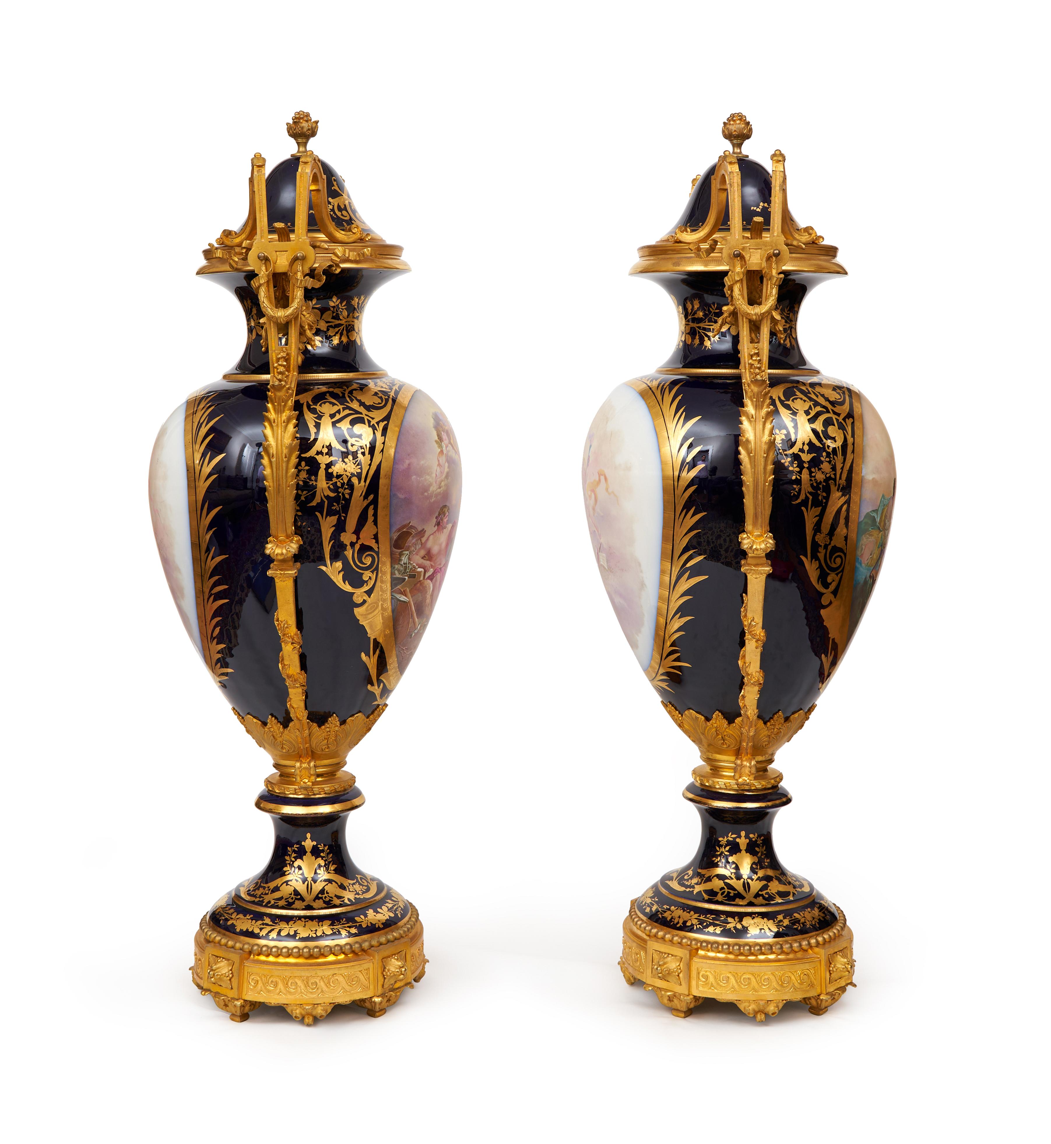 The large lidded urns each with a pair of ormolu scrolling handles, the domed covers marked with a Sevres mark to the underside, the porcelain signed 'Jocelyn', depicting classical scenes of gods and goddesses on a cobalt blue ground with gilt