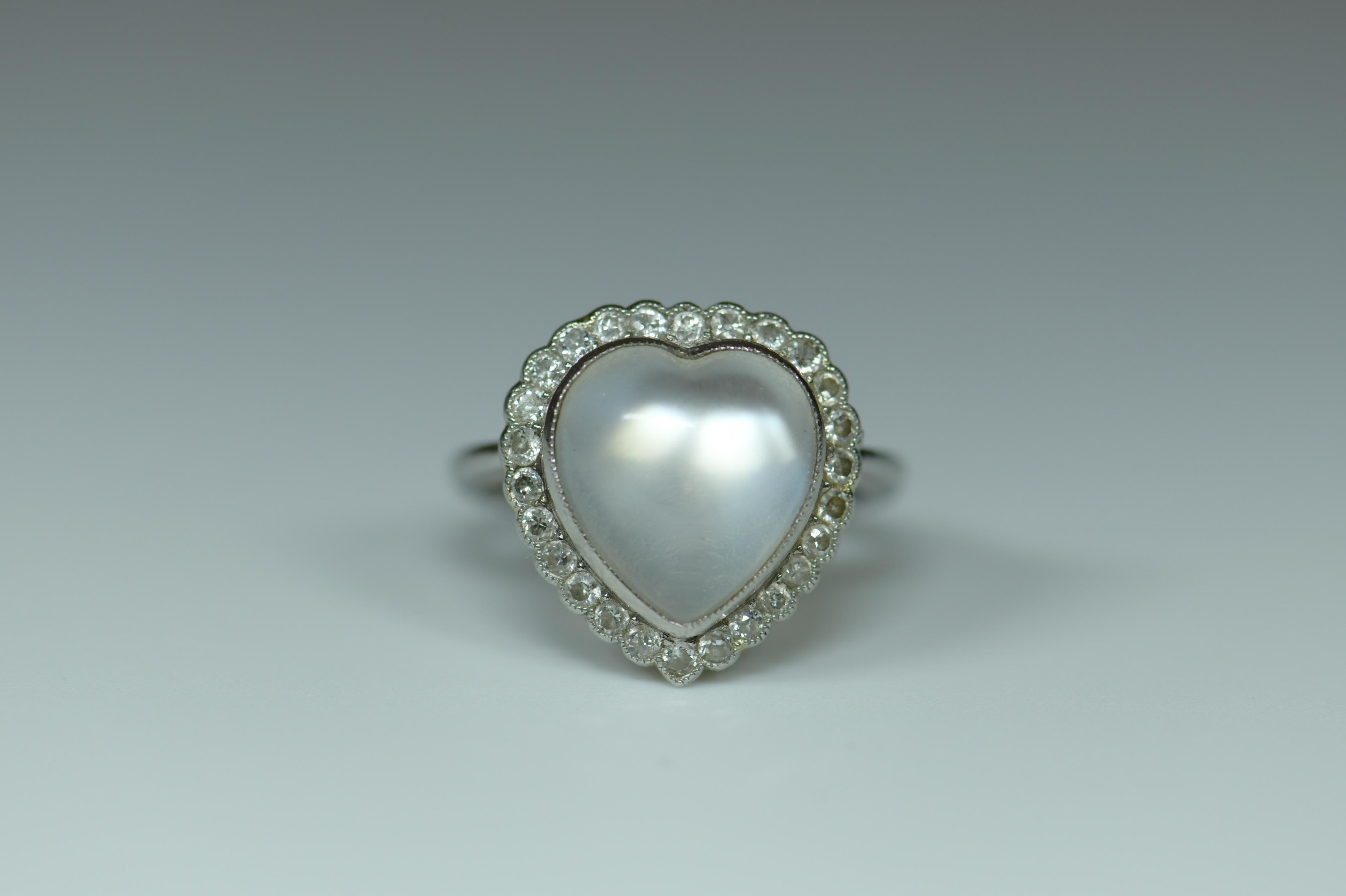 An exquisite moonstone and diamond ring from the early 20th century. This alluring and very unusual piece is made of platinum and features a single moonstone in the center of a diamond-encrusted frame. The moonstone has the hand-carved shape of a