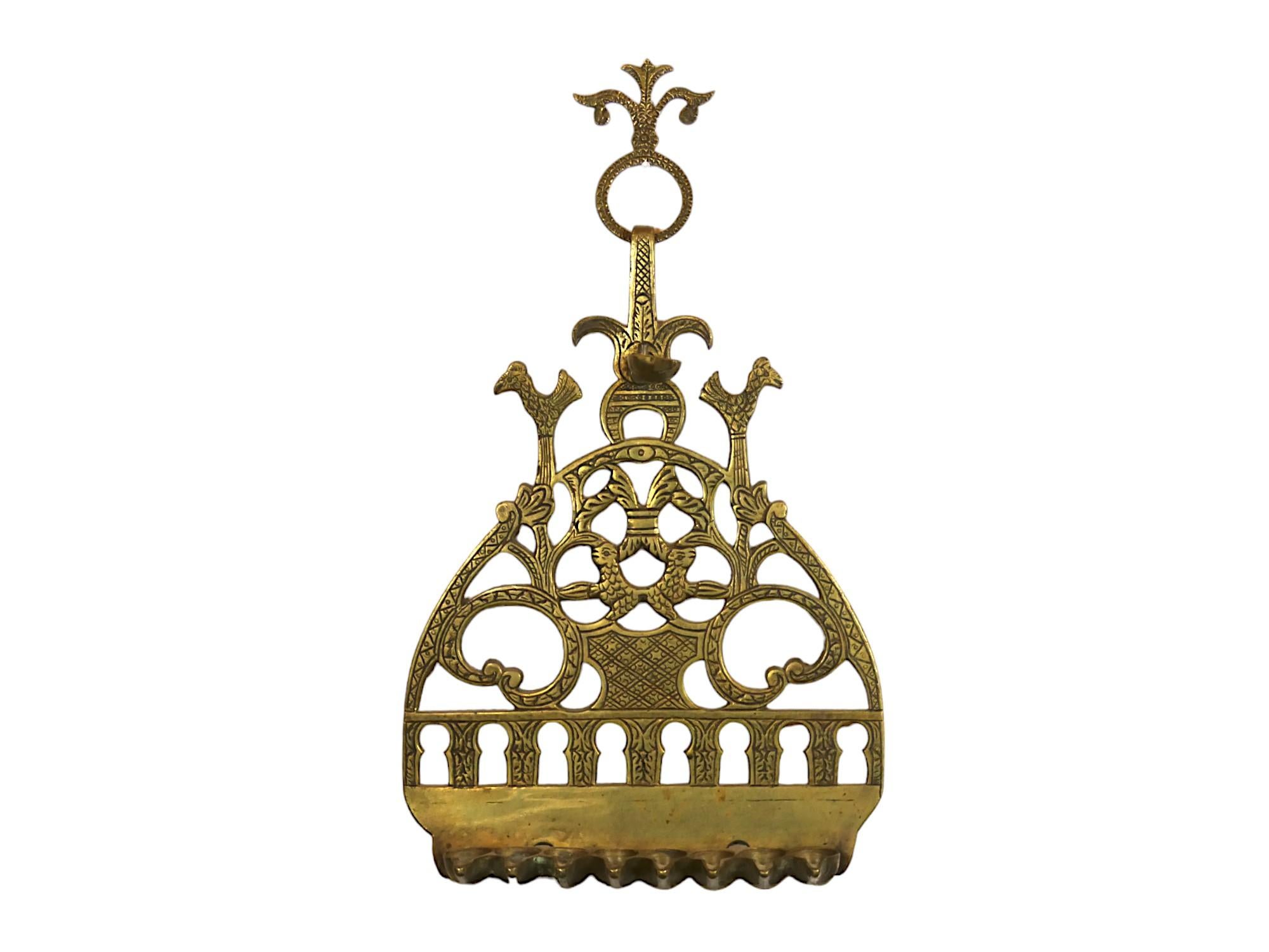 Lampada Hanukkah decorativa a sospensione in ottone realizzata in Marocco alla fine del XIX secolo.

Molteplici temi cabalistici e simboli protettivi nascosti adornano la piastra posteriore di questa lampada di Hannukah, a partire dalla parte