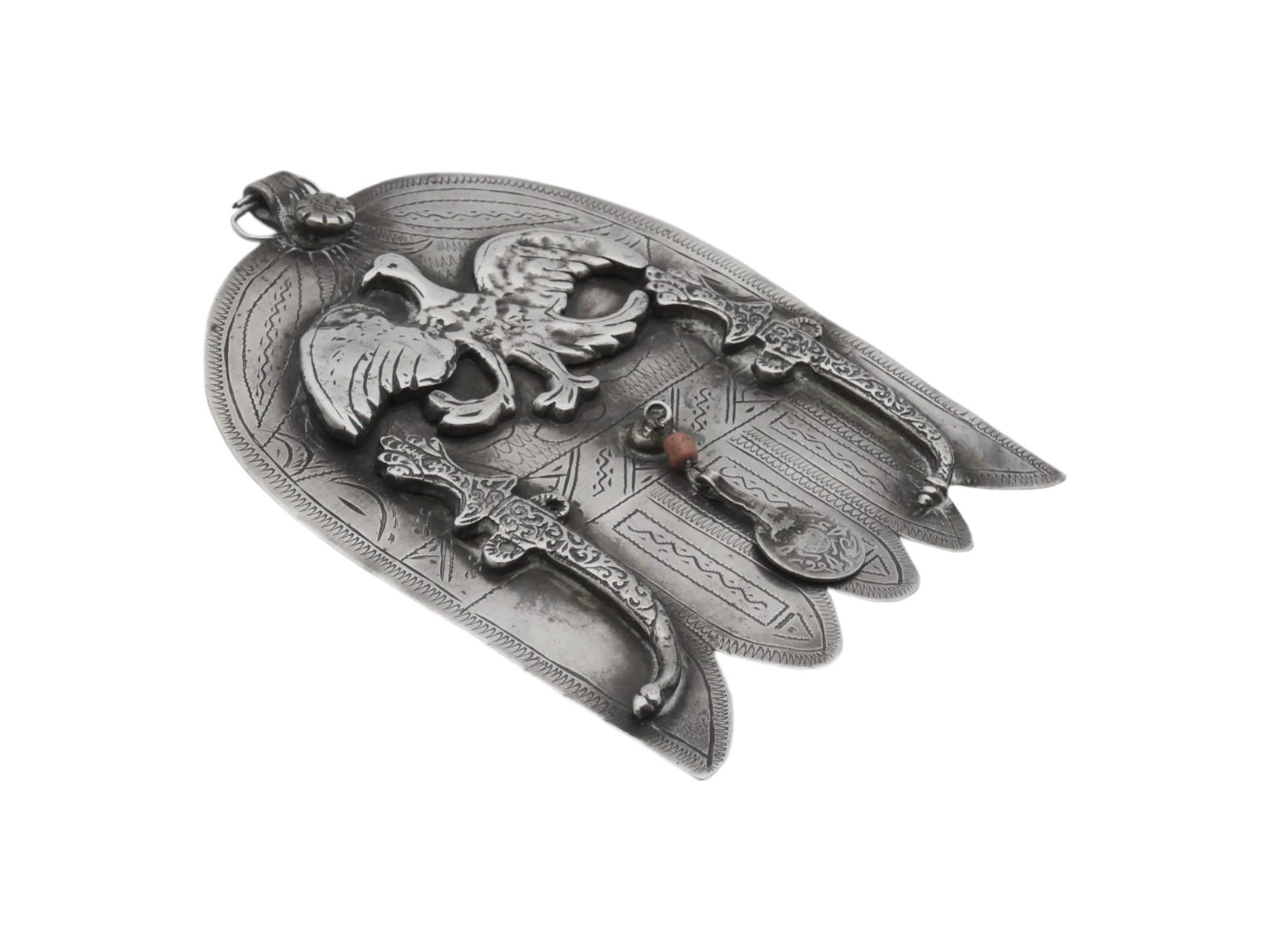 A Silver Hamsa from early 20th-century Morocco is an exquisite artifact that blends Jewish symbolism with North African craftsmanship. 

The Hamsa, a hand-shaped amulet believed to ward off the evil eye and bring blessings, holds significant